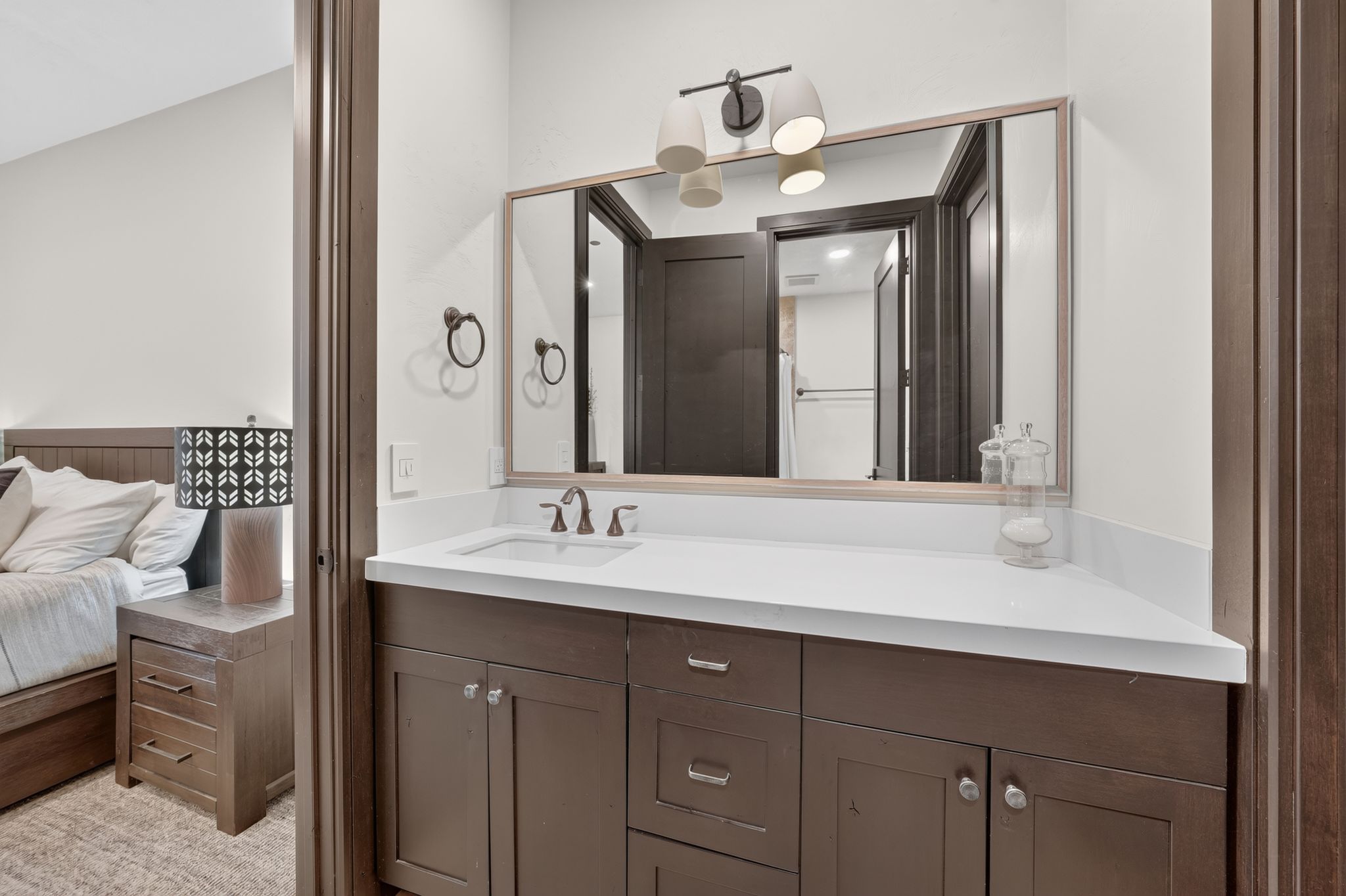Bathroom vanity featuring a single undermount sink, a white countertop, and dark wood cabinetry