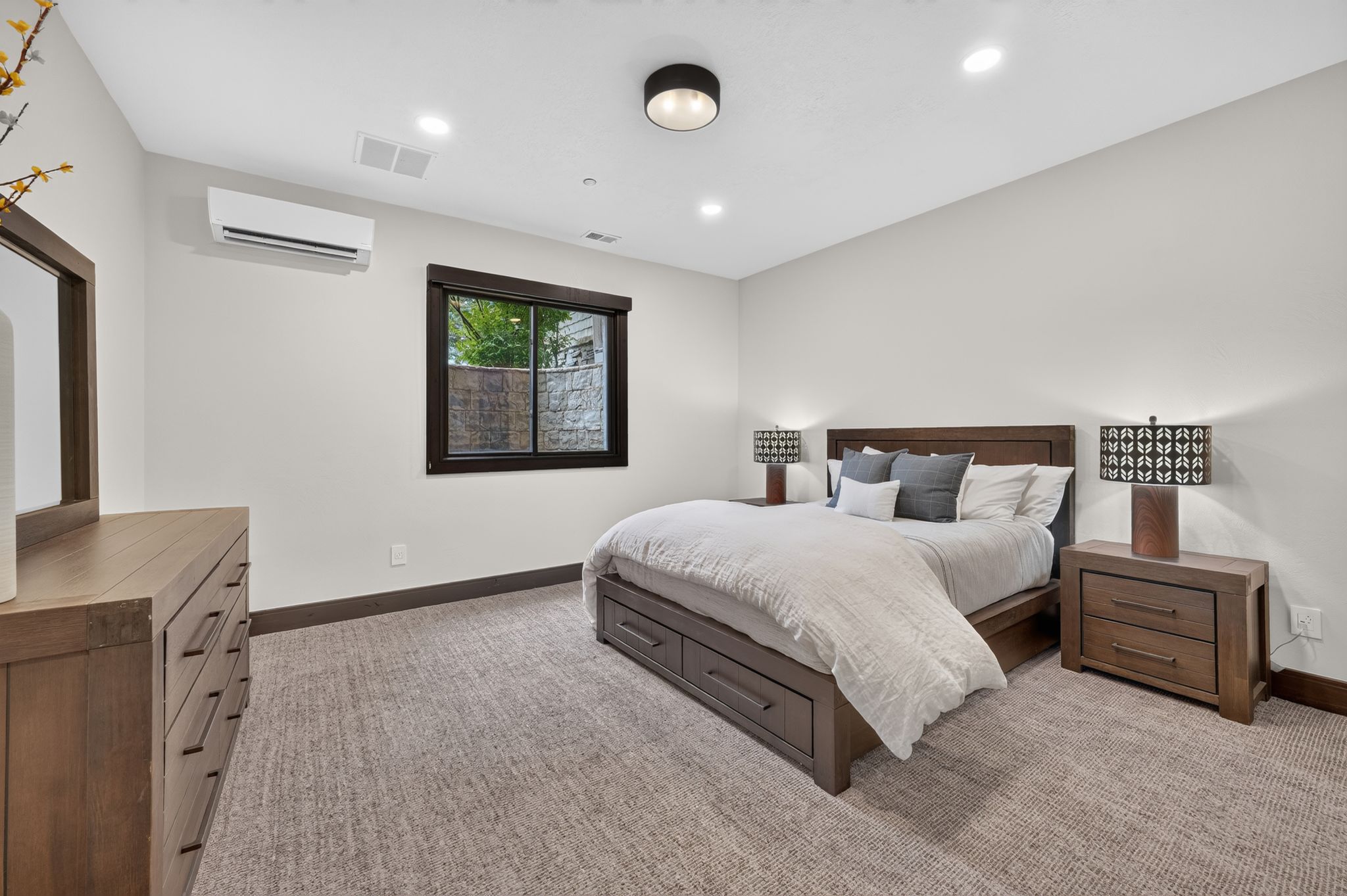 Carpeted bedroom featuring a dark wood window frame, recessed lighting, and a wall-mounted mini-split HVAC unit