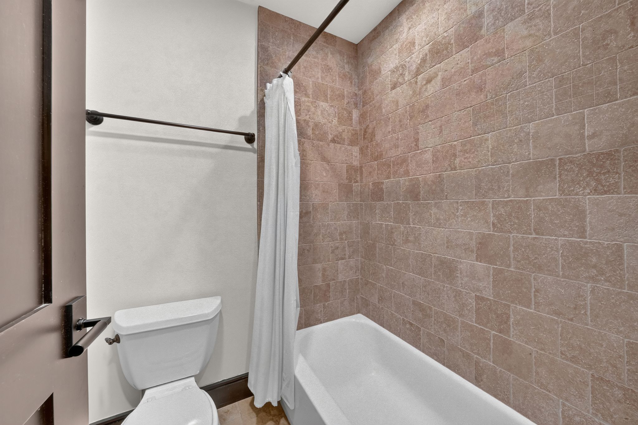 Bathroom featuring a white bathtub, subway tile shower surround, and a white toilet