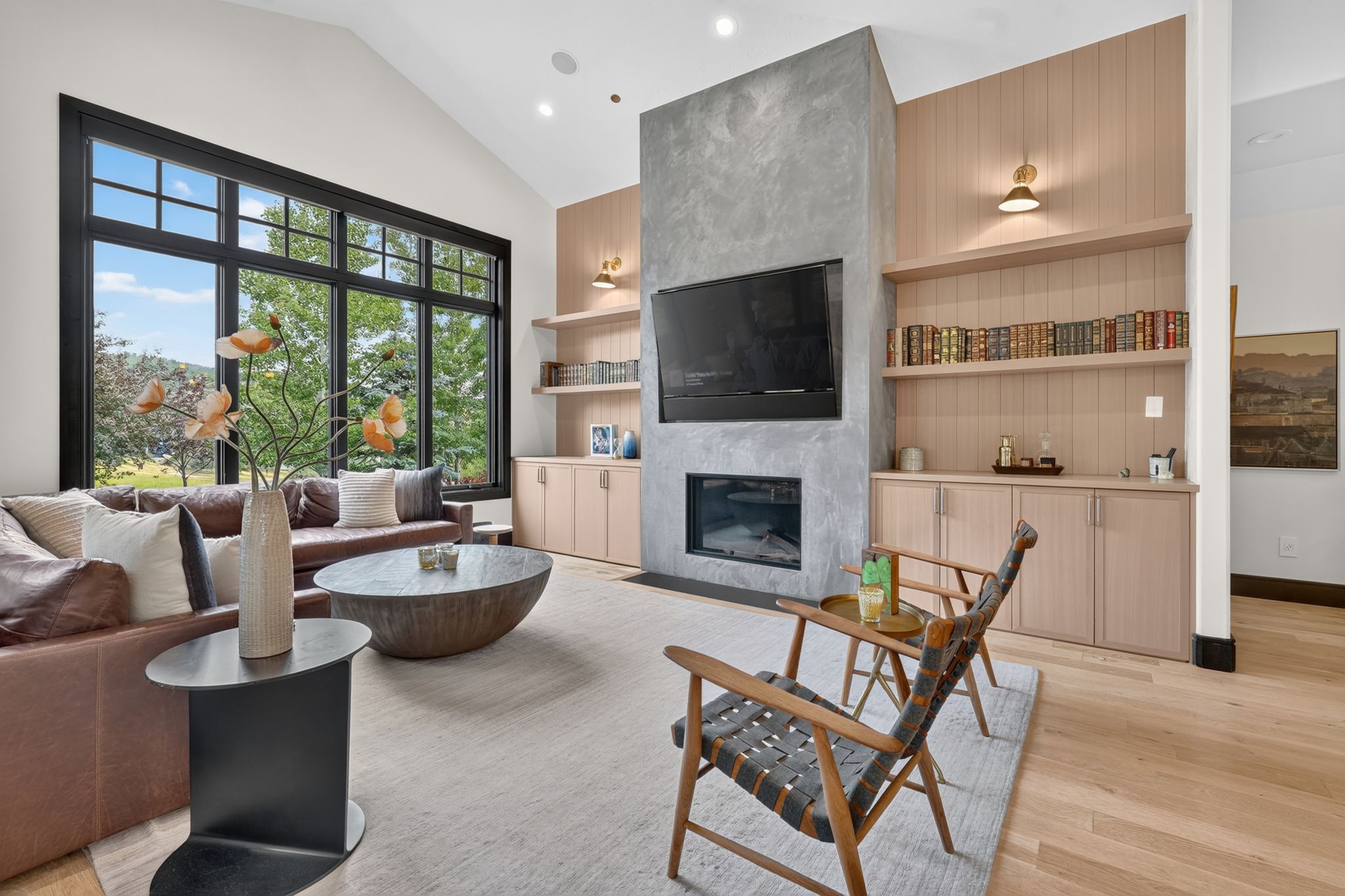 Spacious living area featuring a vaulted ceiling and an expansive window with black trim