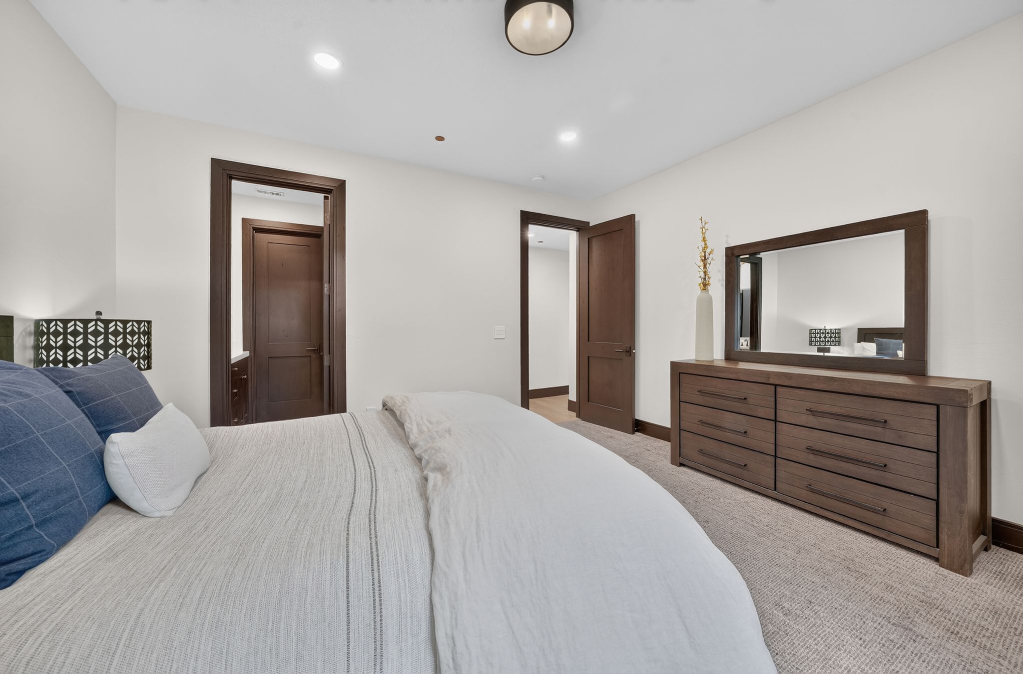 Carpeted bedroom featuring white walls, recessed lighting, and dark wood-finish trim and doors