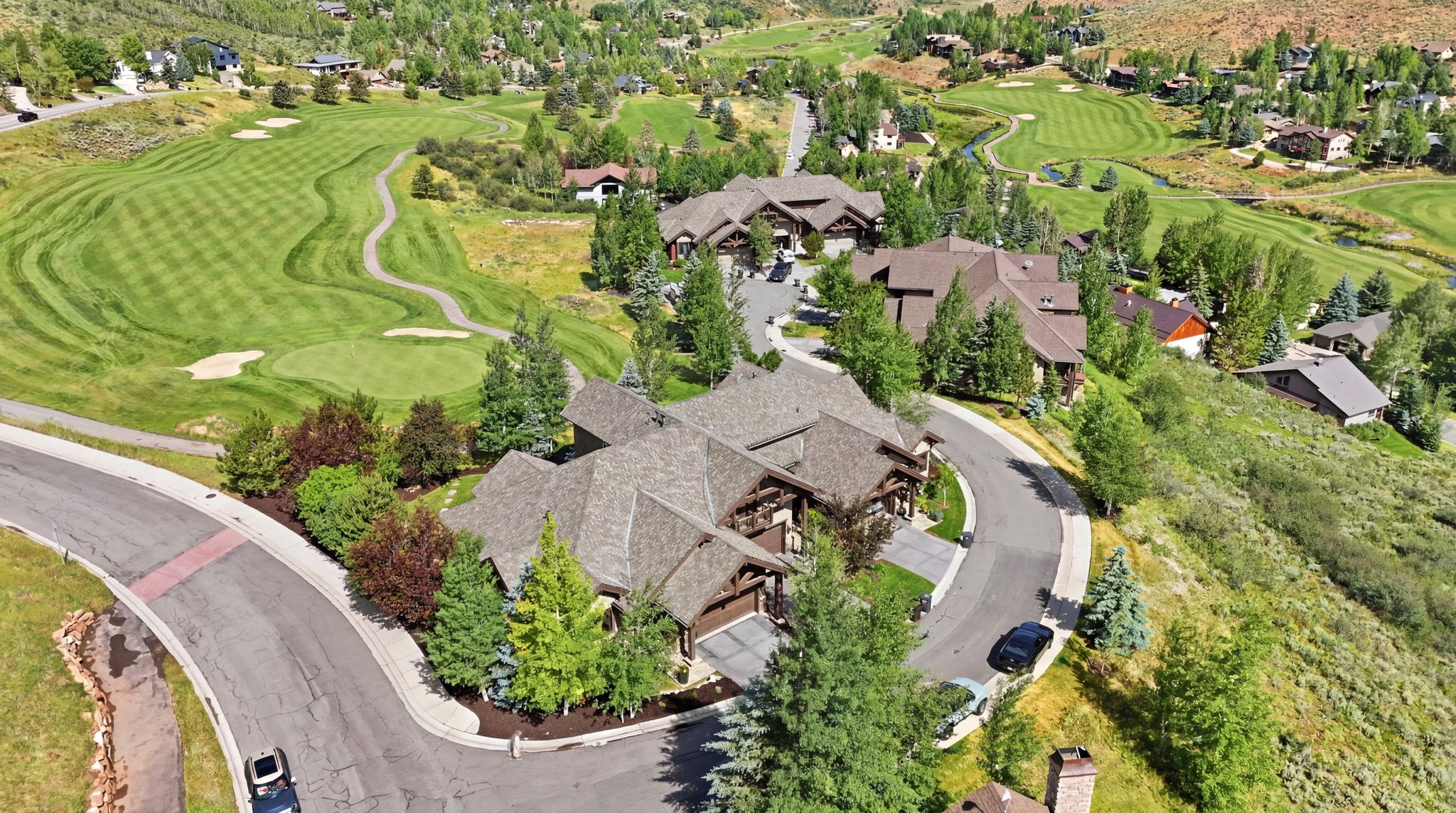 Hillside property featuring multi-story residences with shingle roofs and stone accents