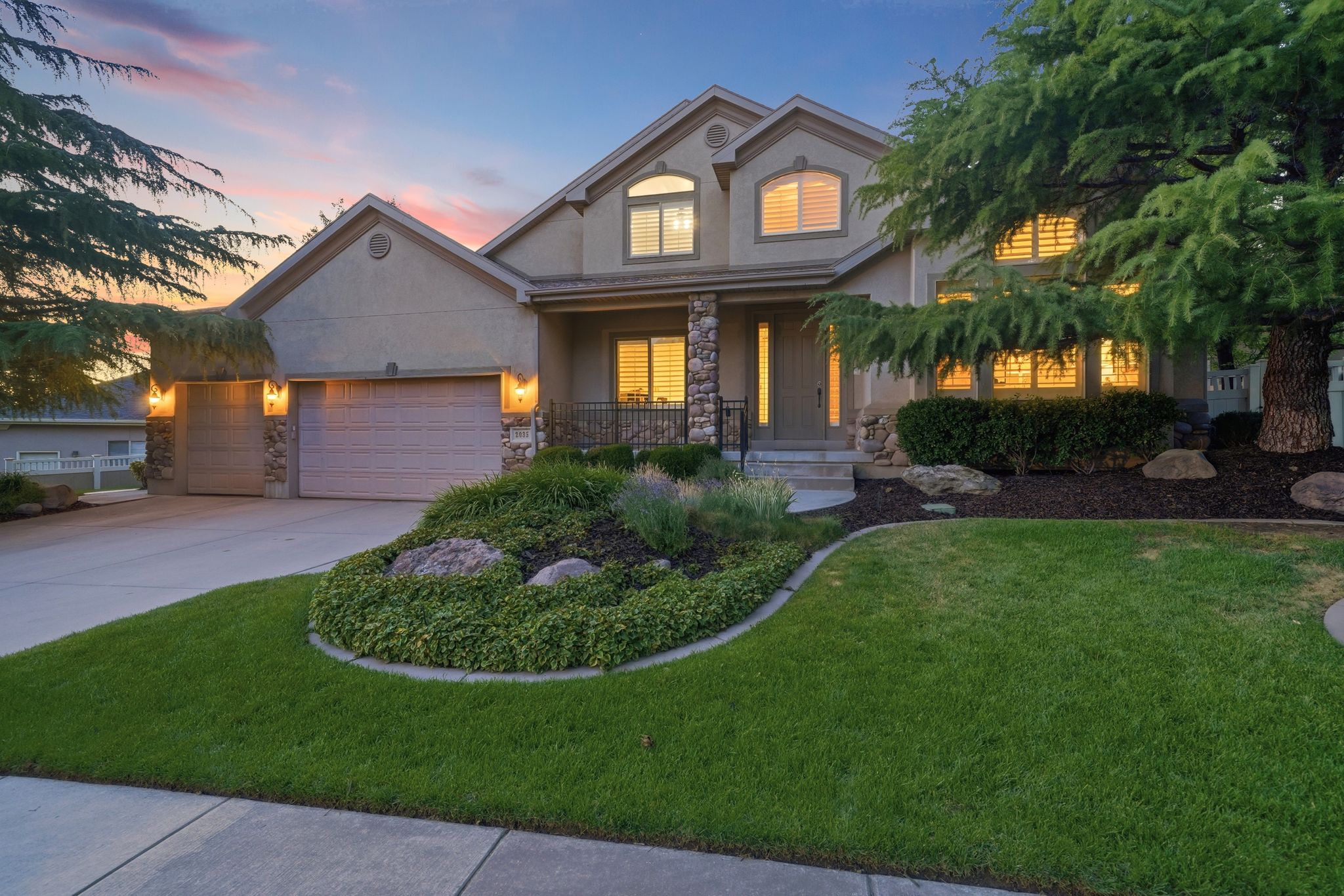 Stucco exterior with stone accents and twin garage doors
