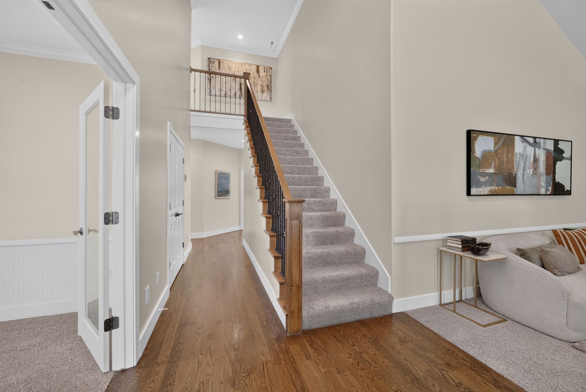 Grand foyer with a carpeted staircase featuring a wrought iron and wood banister