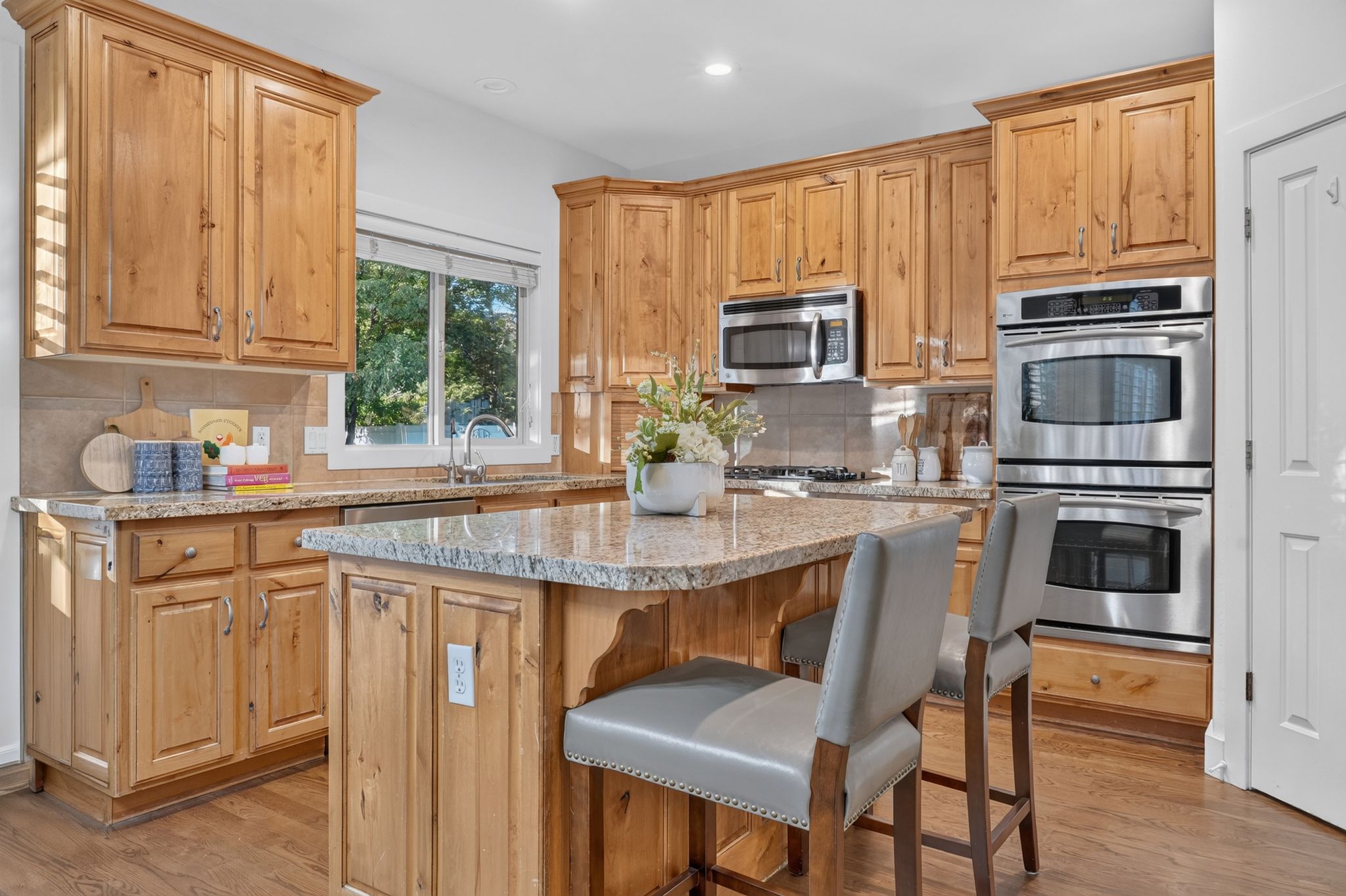Well-appointed kitchen featuring wood cabinetry, light-toned countertops, and stainless steel appliances, including double wall ovens