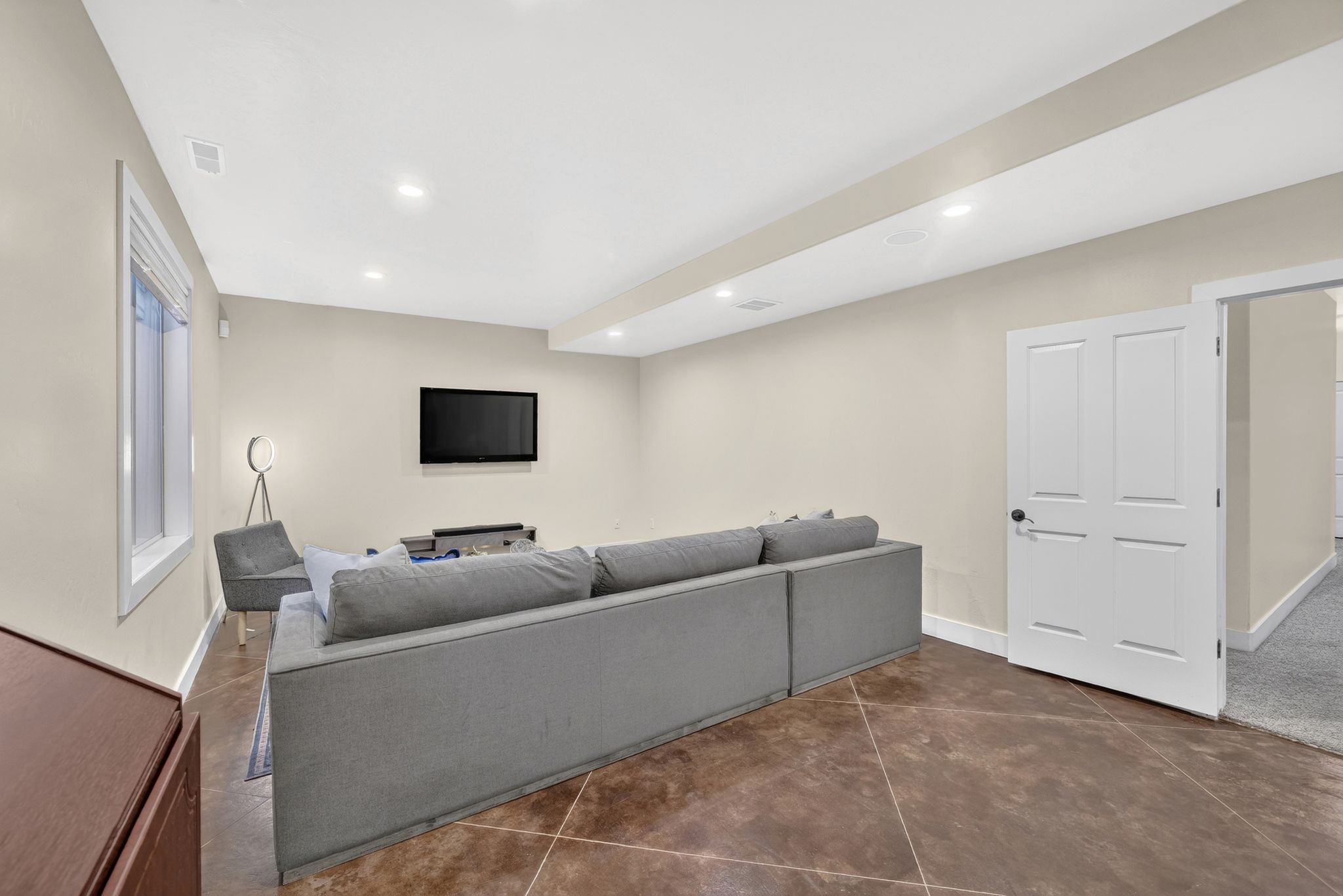 Spacious room featuring neutral painted walls, recessed lighting, white trim, a single window, and a white paneled door