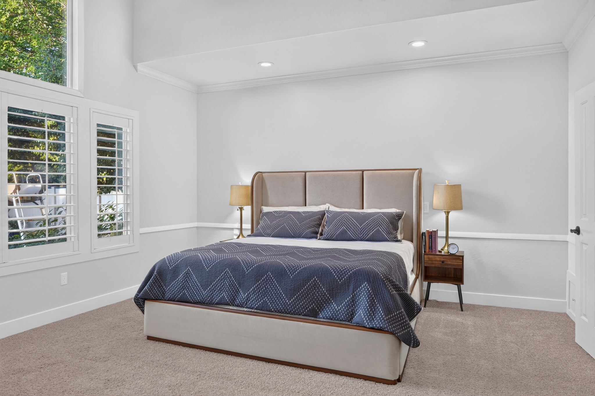 Bedroom featuring neutral paint, crown molding, and wainscoting details