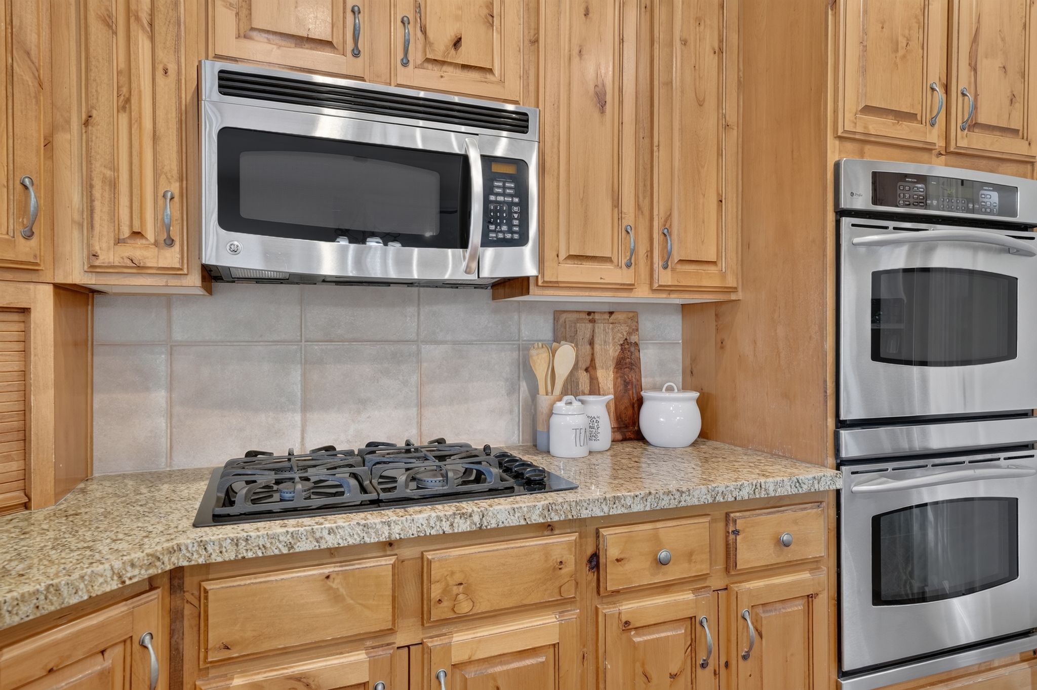 Kitchen featuring light wood cabinetry, stainless steel appliances, a built-in microwave, double wall ovens, and a gas cooktop