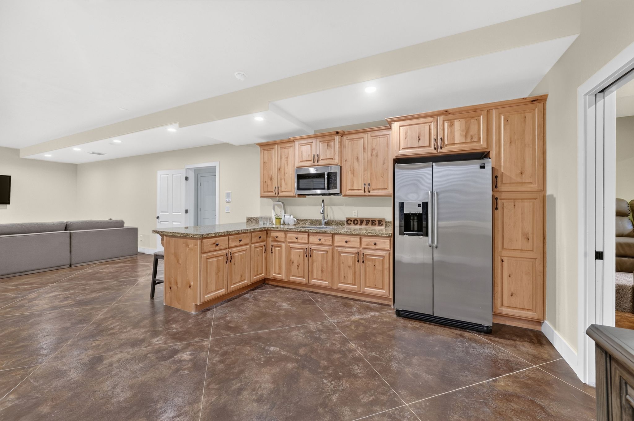 L-shaped kitchen area featuring wood cabinetry, granite countertops, stainless steel appliances, and a built-in microwave