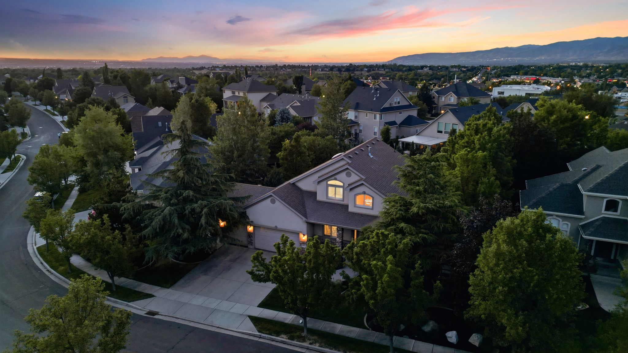 Suburban home featuring a two-car garage, mature landscaping, and a curvilinear street