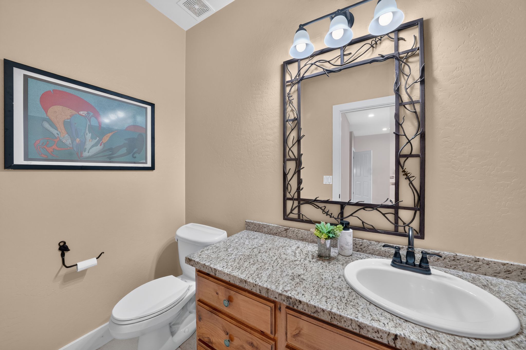Bathroom vanity featuring a speckled countertop, an oval undermount sink, and a dark bronze faucet