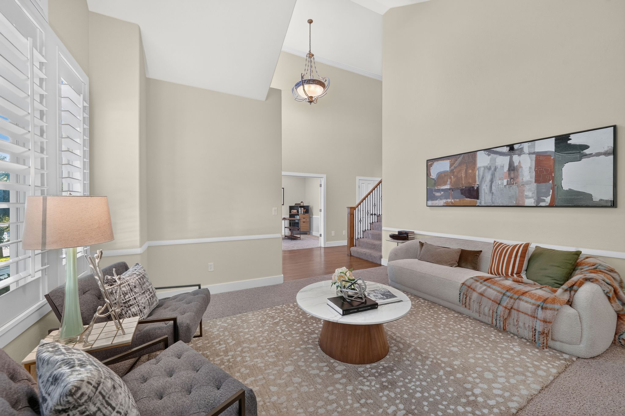 Two-story living area with vaulted ceilings, crown molding, and plantation shutters