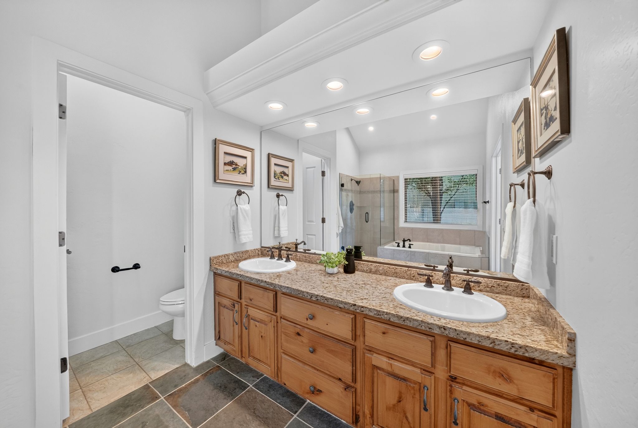 Dual basin vanity featuring wood-finish cabinetry, a stone-finish countertop, and bronze-finish fixtures