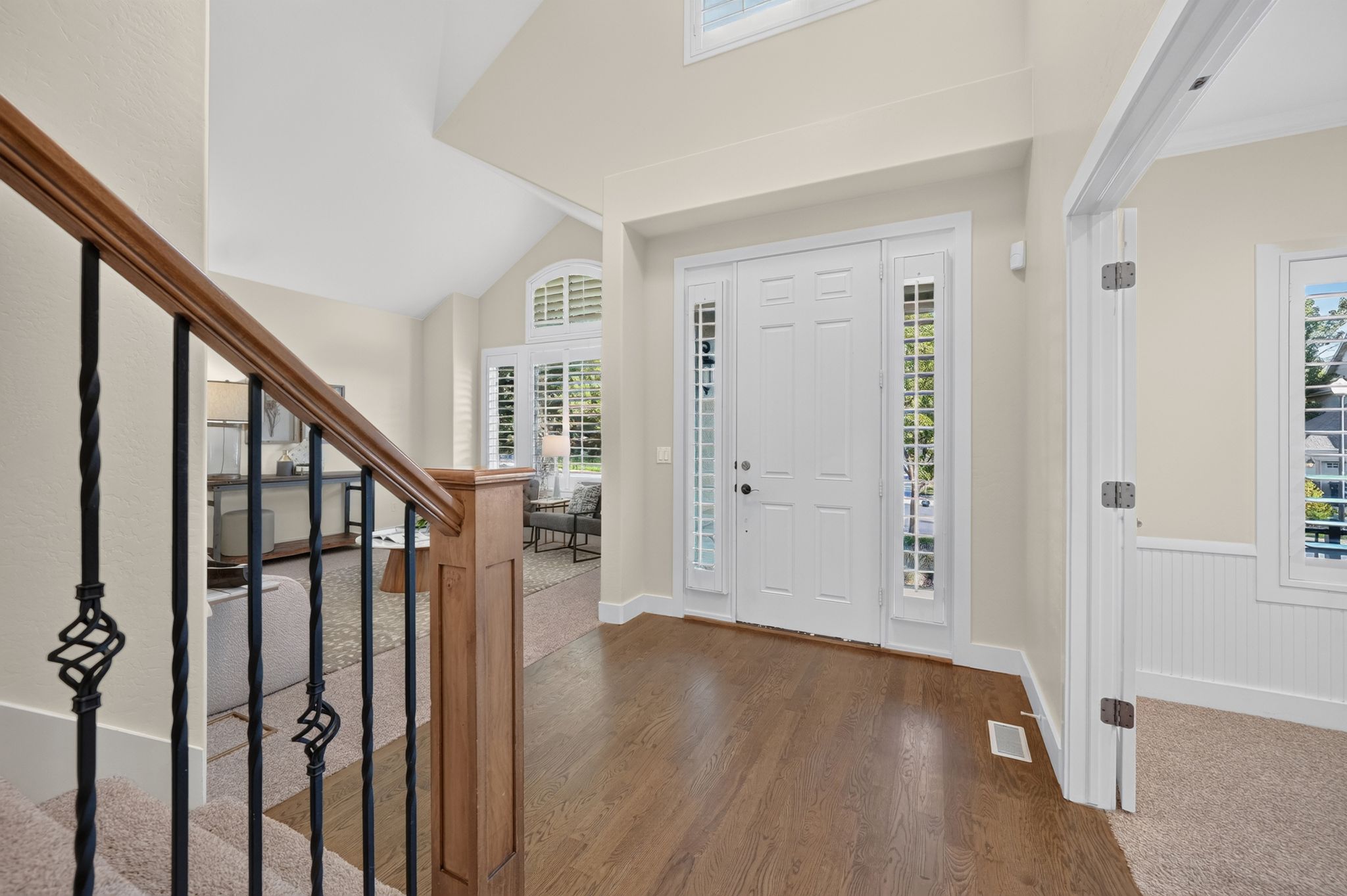 Foyer entry with wood-finish flooring, a double-panel front door with sidelights, and an iron baluster staircase