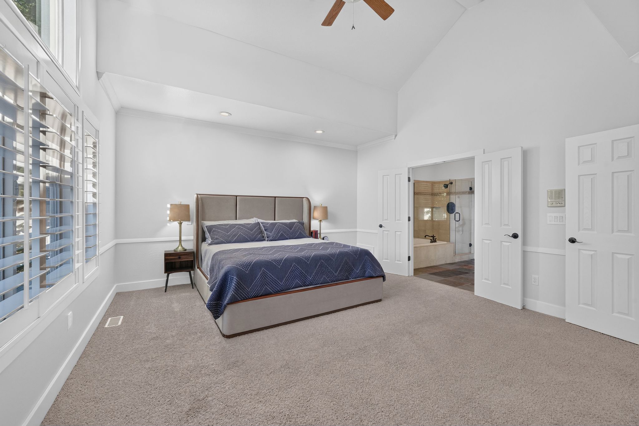 Carpeted bedroom with vaulted ceilings and a ceiling fan