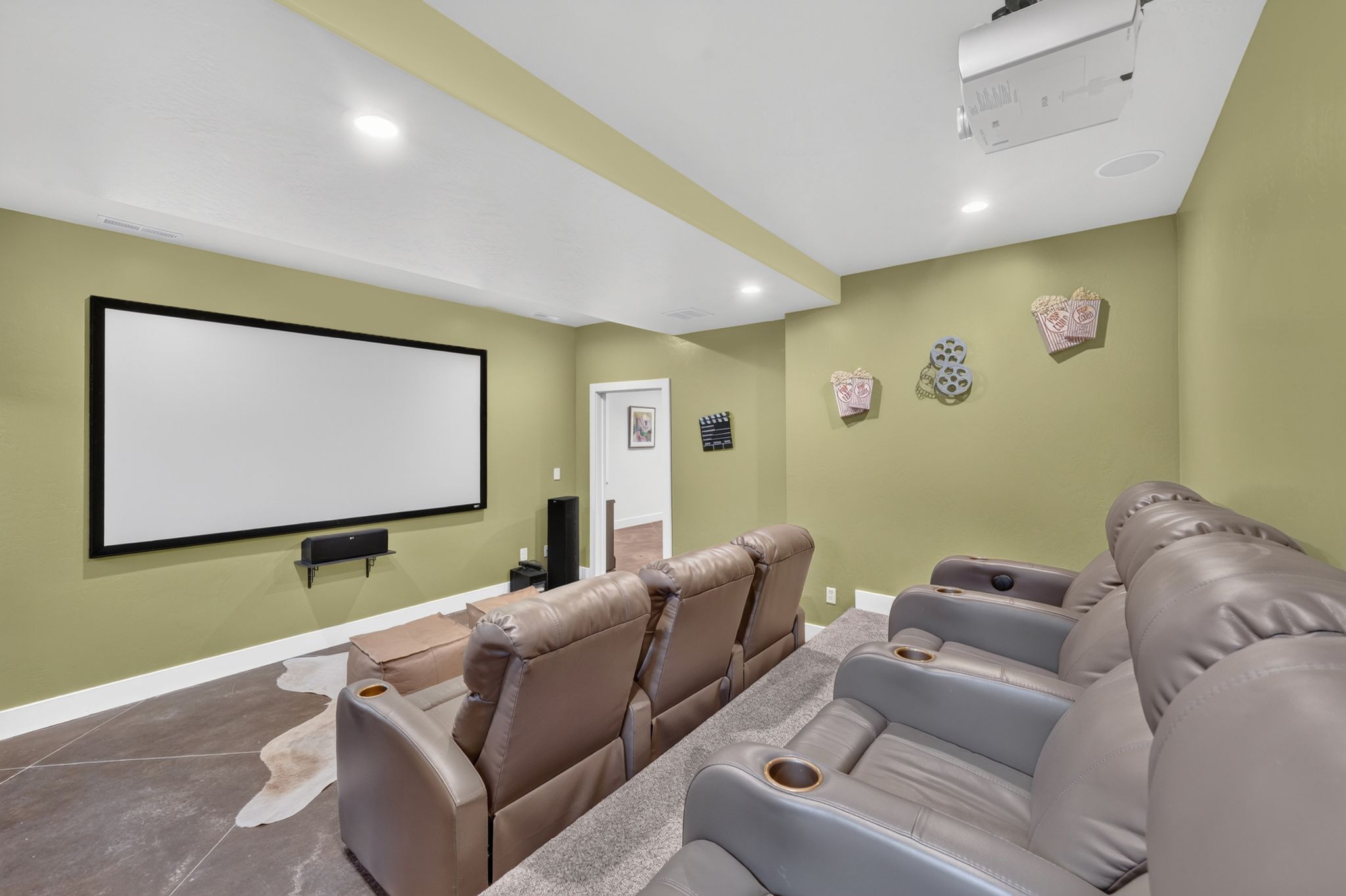 Dedicated home theater featuring a large projection screen, ceiling-mounted projector, and integrated ceiling speakers
