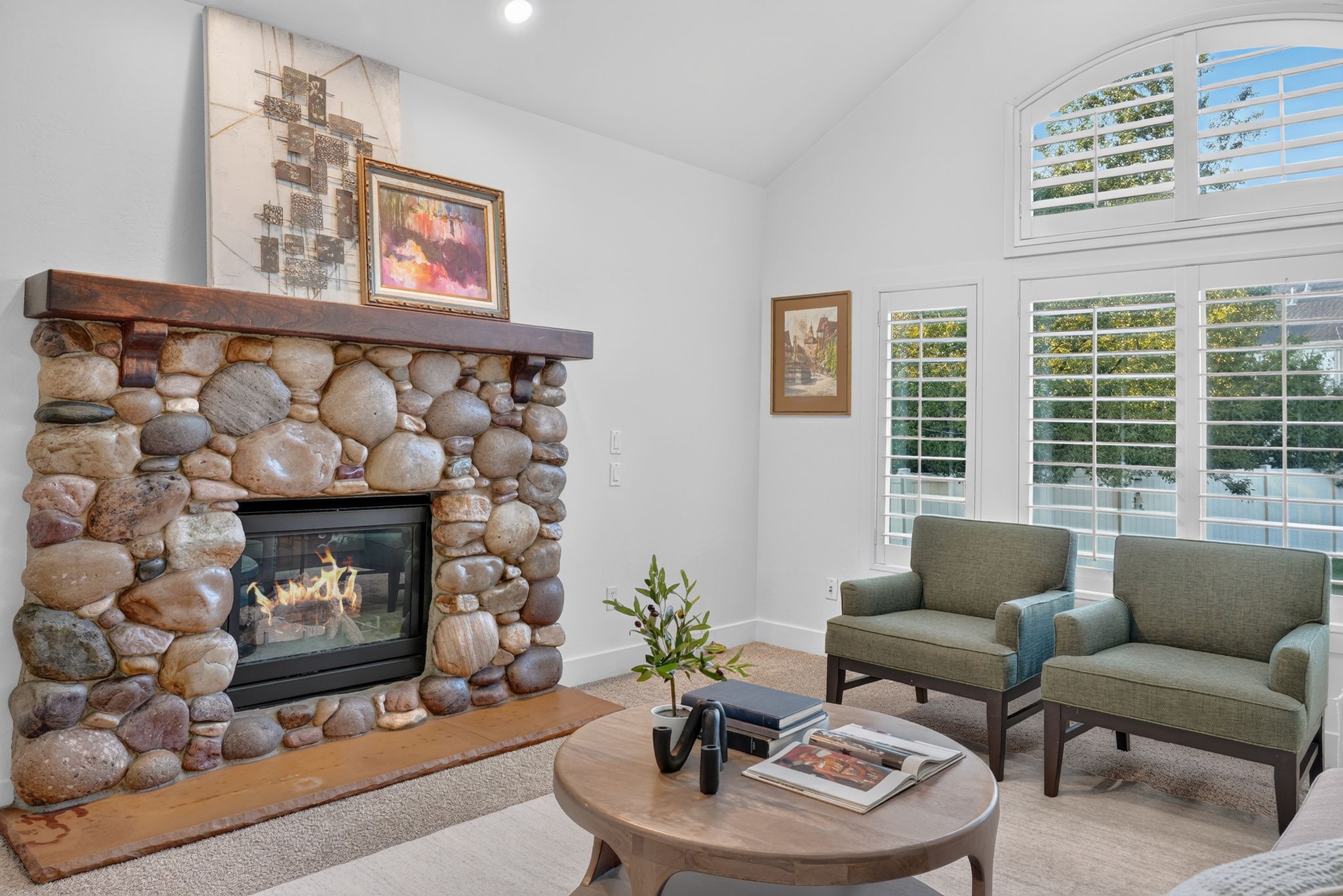 River rock fireplace with a dark wood mantel and a stone hearth