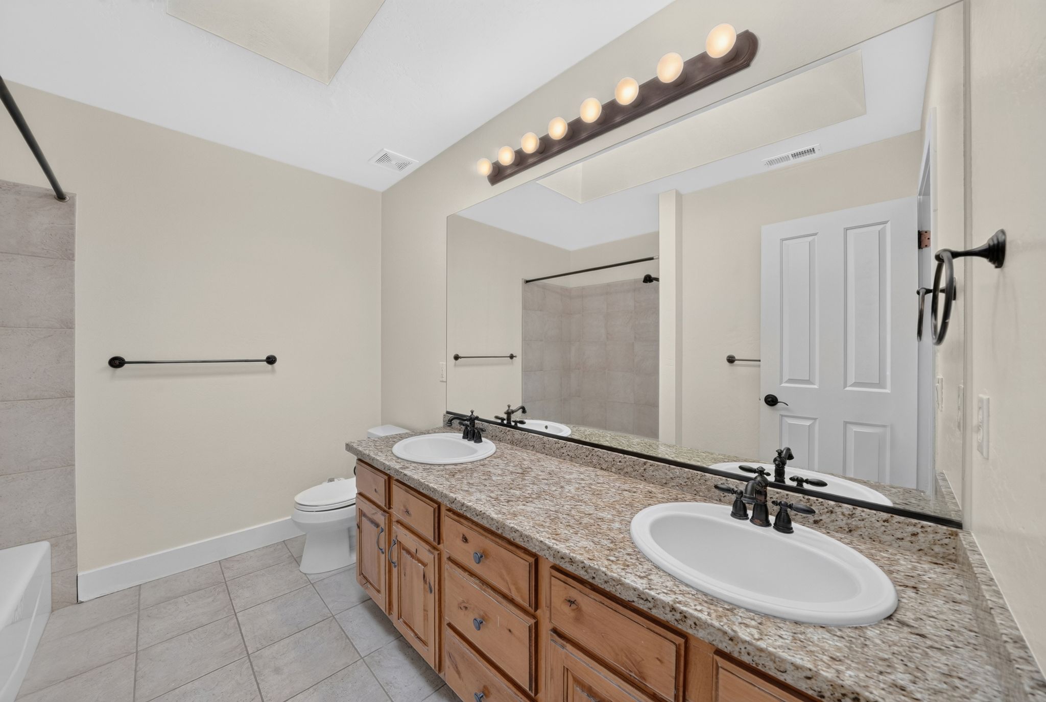 Double vanity featuring wood cabinetry, undermount sinks, and a speckled countertop