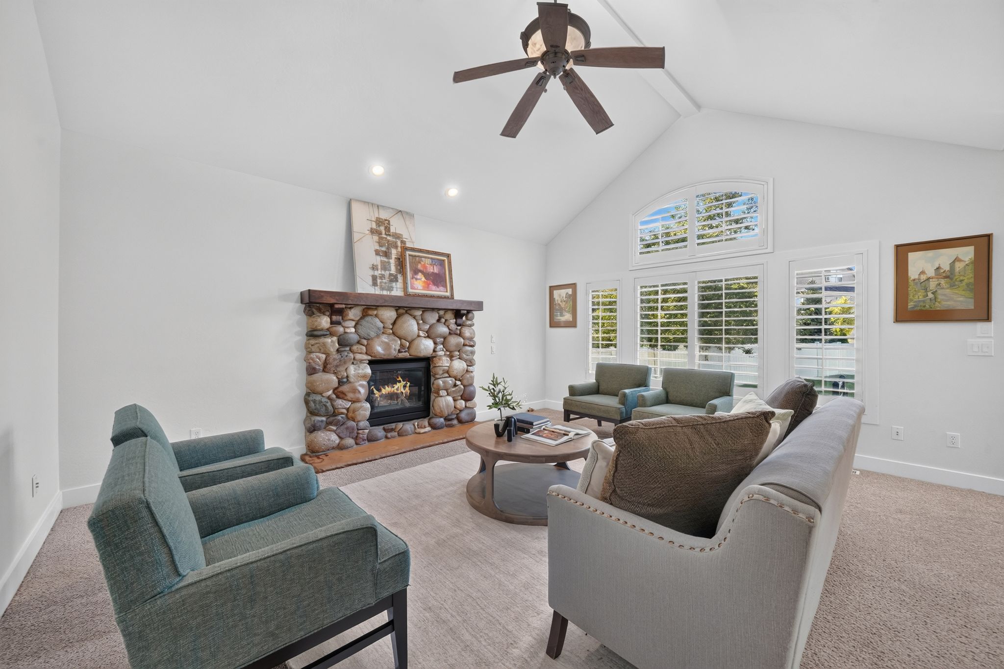 Living space featuring a stone fireplace with a wood mantle, vaulted ceiling, and recessed lighting