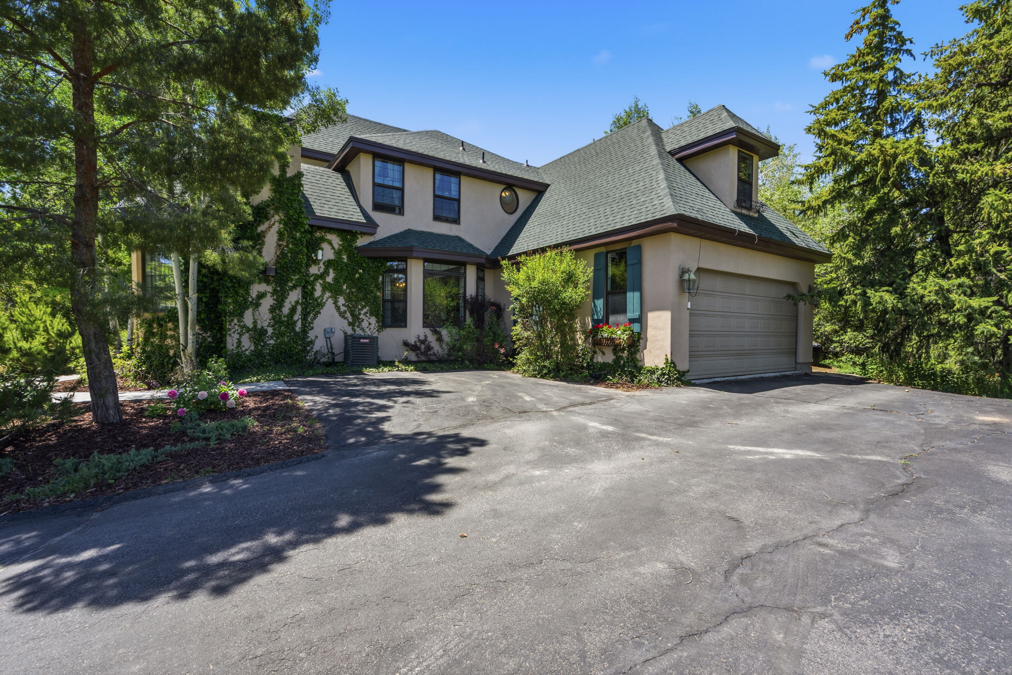 Stucco exterior with a multi-level green shingle roof and dormer window