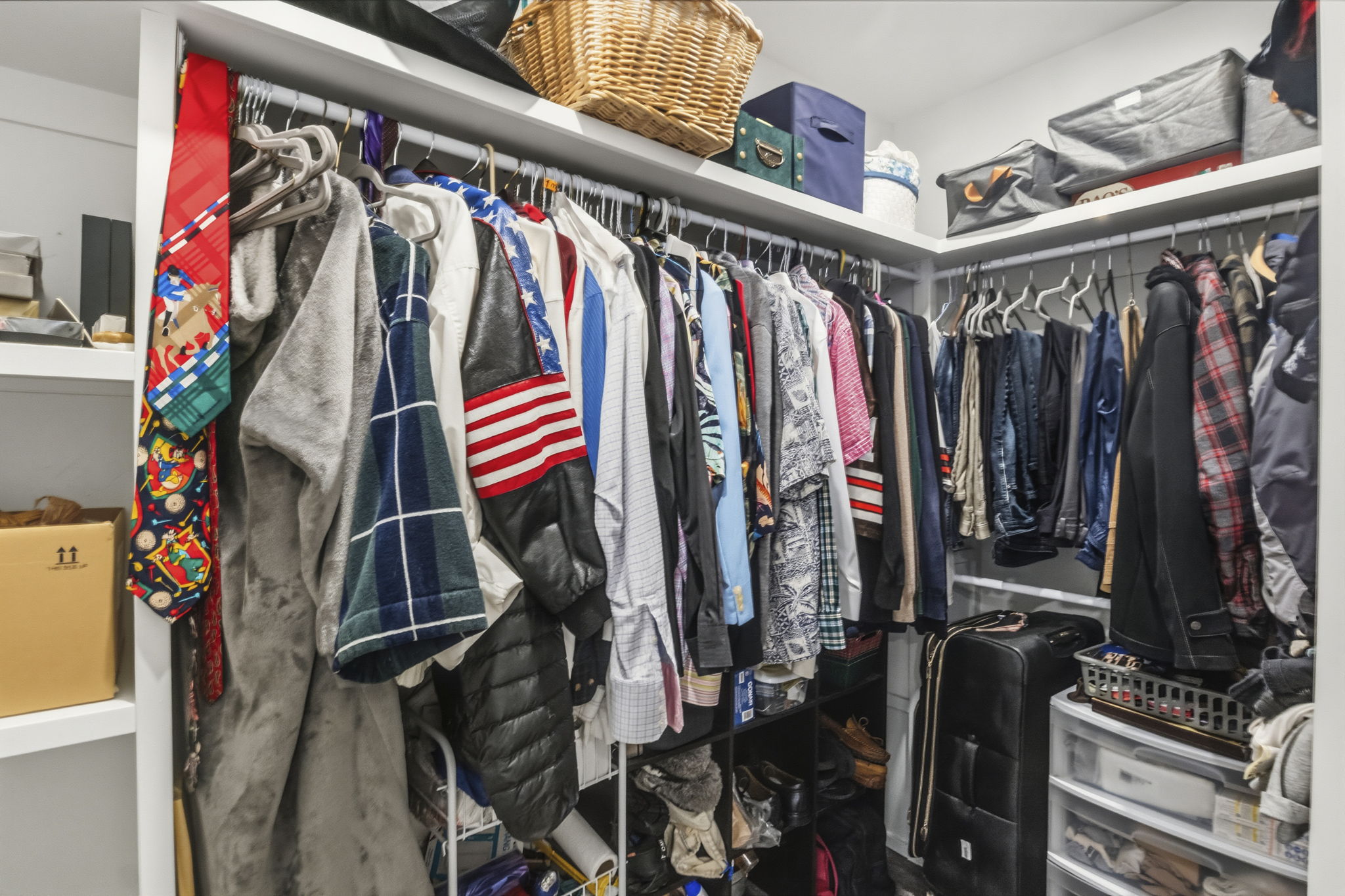 Walk-in closet featuring white built-in shelving, multiple hanging rods, and corner storage solutions