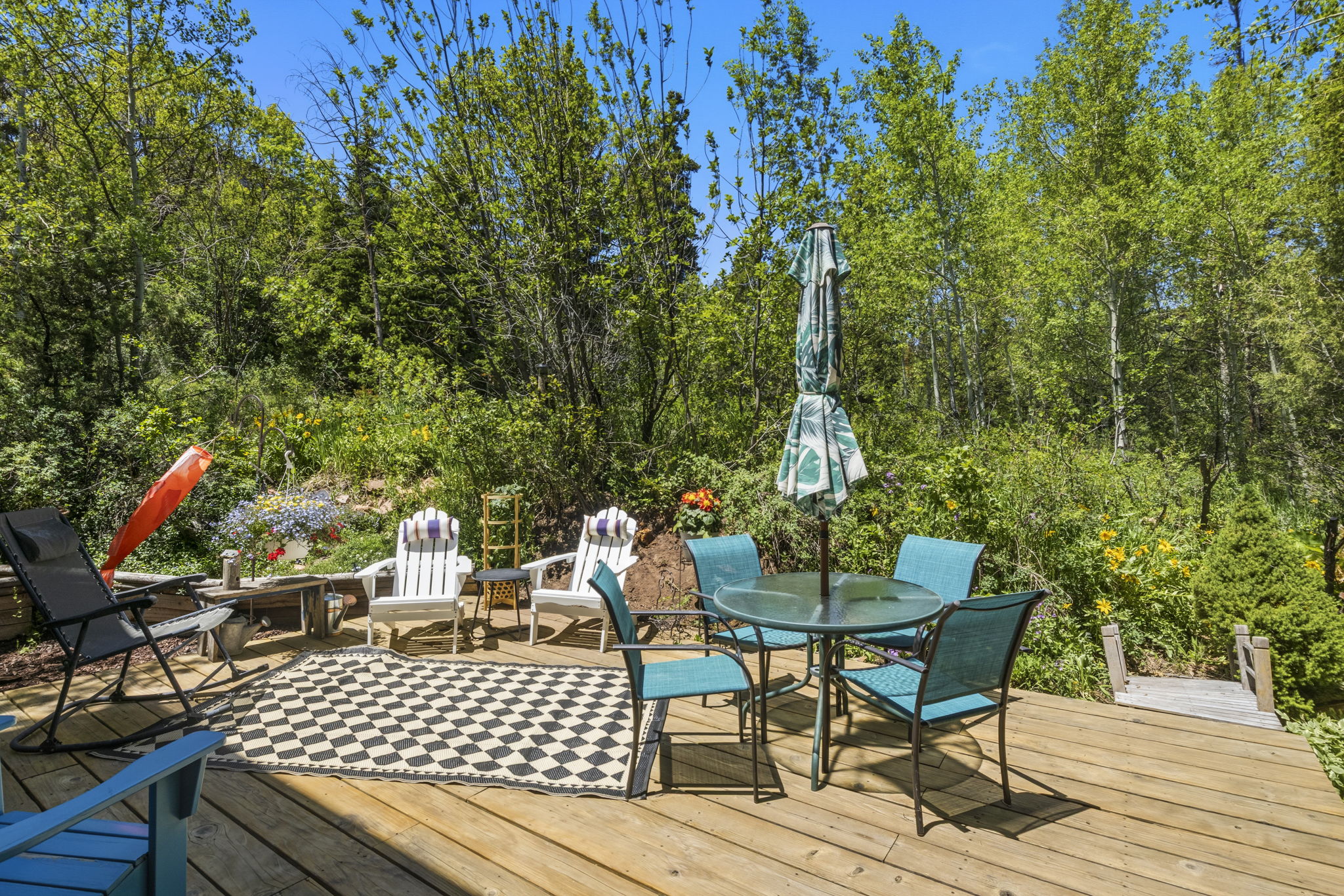 Expansive outdoor wood-finish deck surrounded by lush green foliage and mature trees