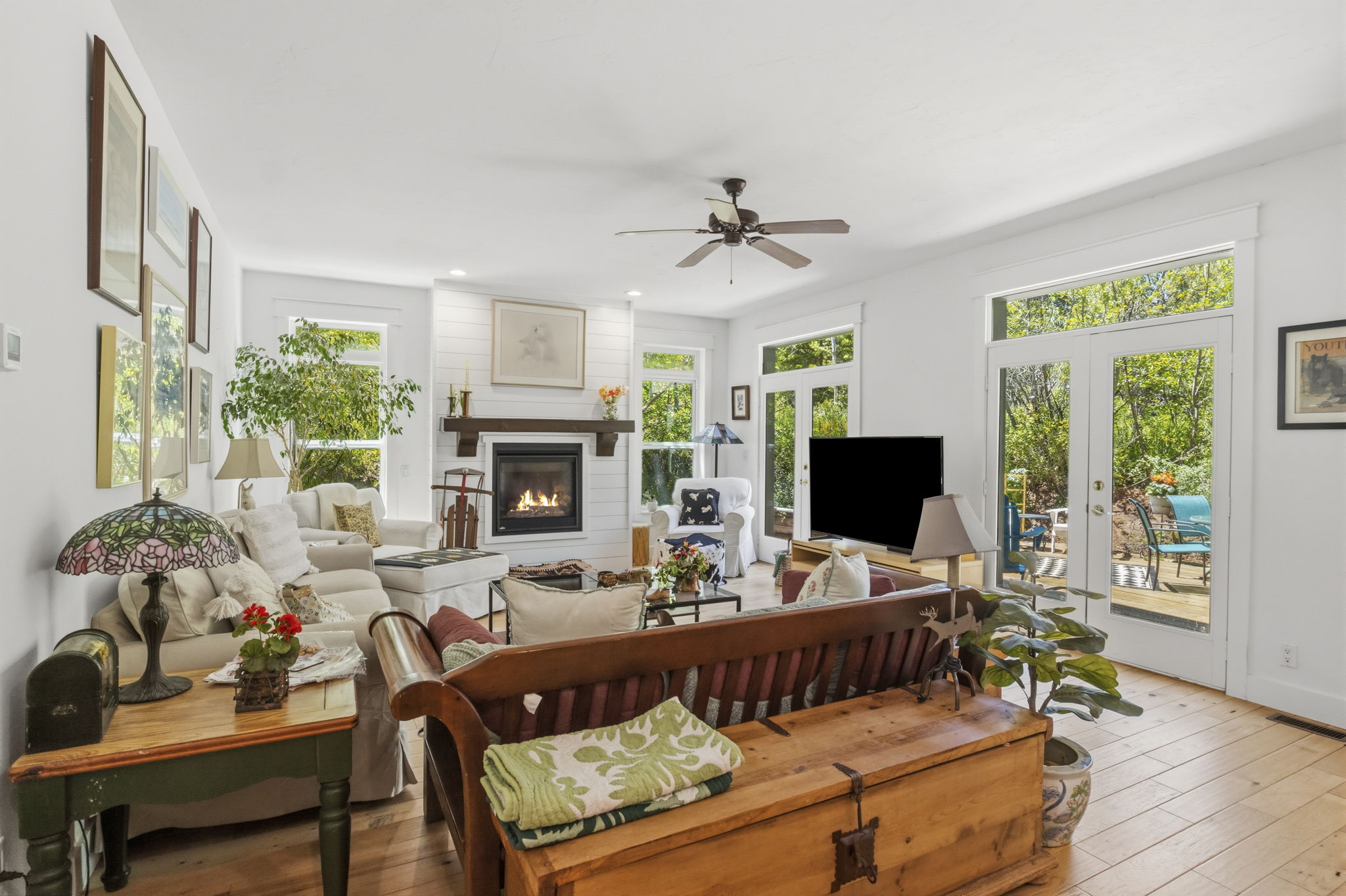 Living area featuring light wood flooring and a white shiplap fireplace with a dark wood mantel