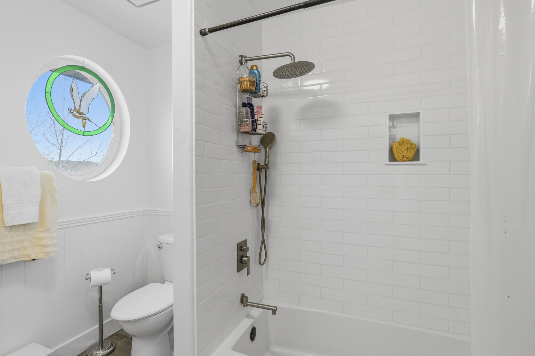 Bathtub with subway tile surround, integrated shower niche, and rain showerhead