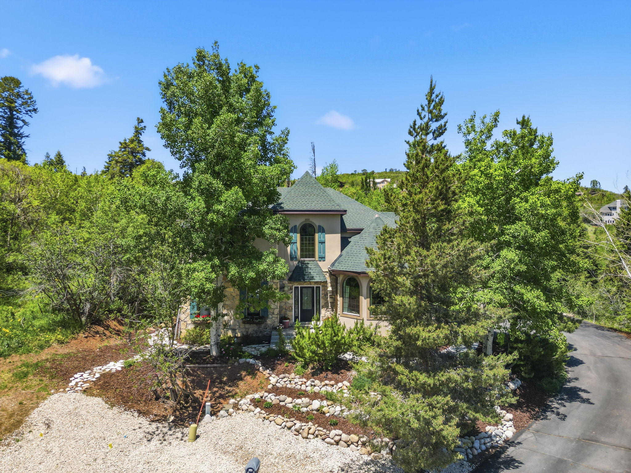Stone and stucco exterior residence featuring a prominent green shingle roof