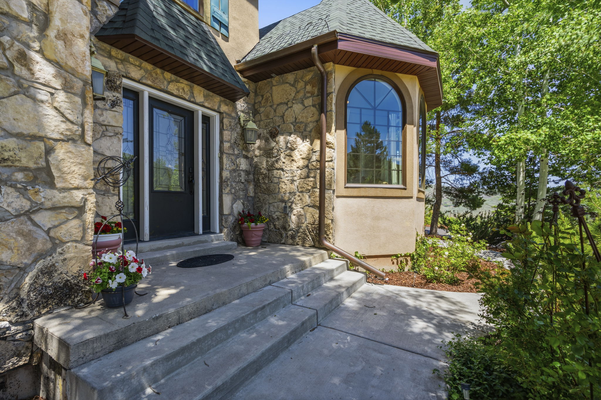 Stone facade entry with a dark-paneled door featuring decorative glass inserts and a side light