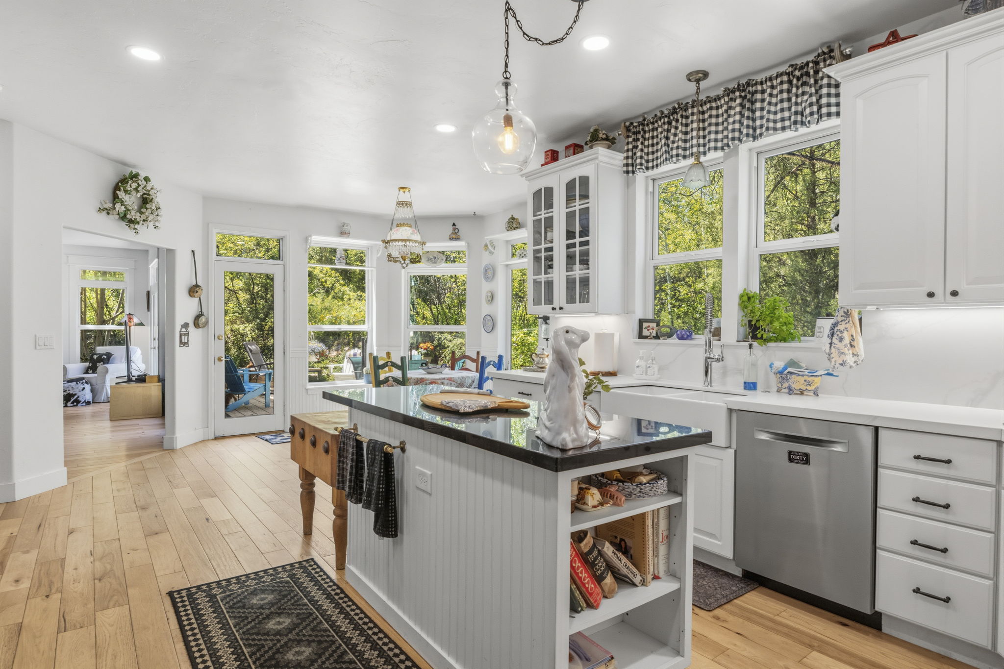 Bright kitchen featuring light wood-finish flooring, white cabinetry, and a central island with a dark countertop