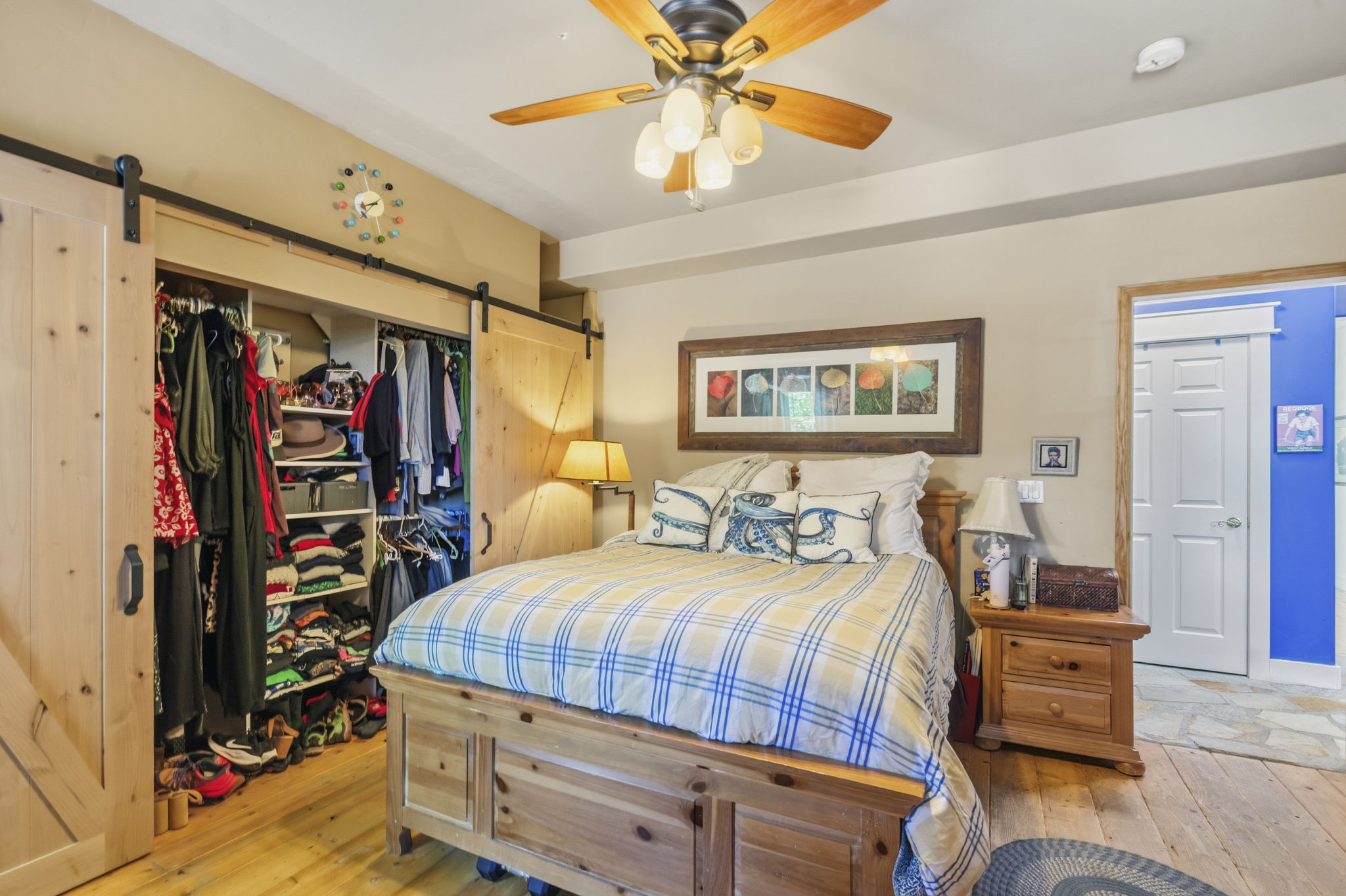 Bedroom featuring wood-finish flooring, a ceiling fan with integrated lighting, and a closet with sliding barn doors