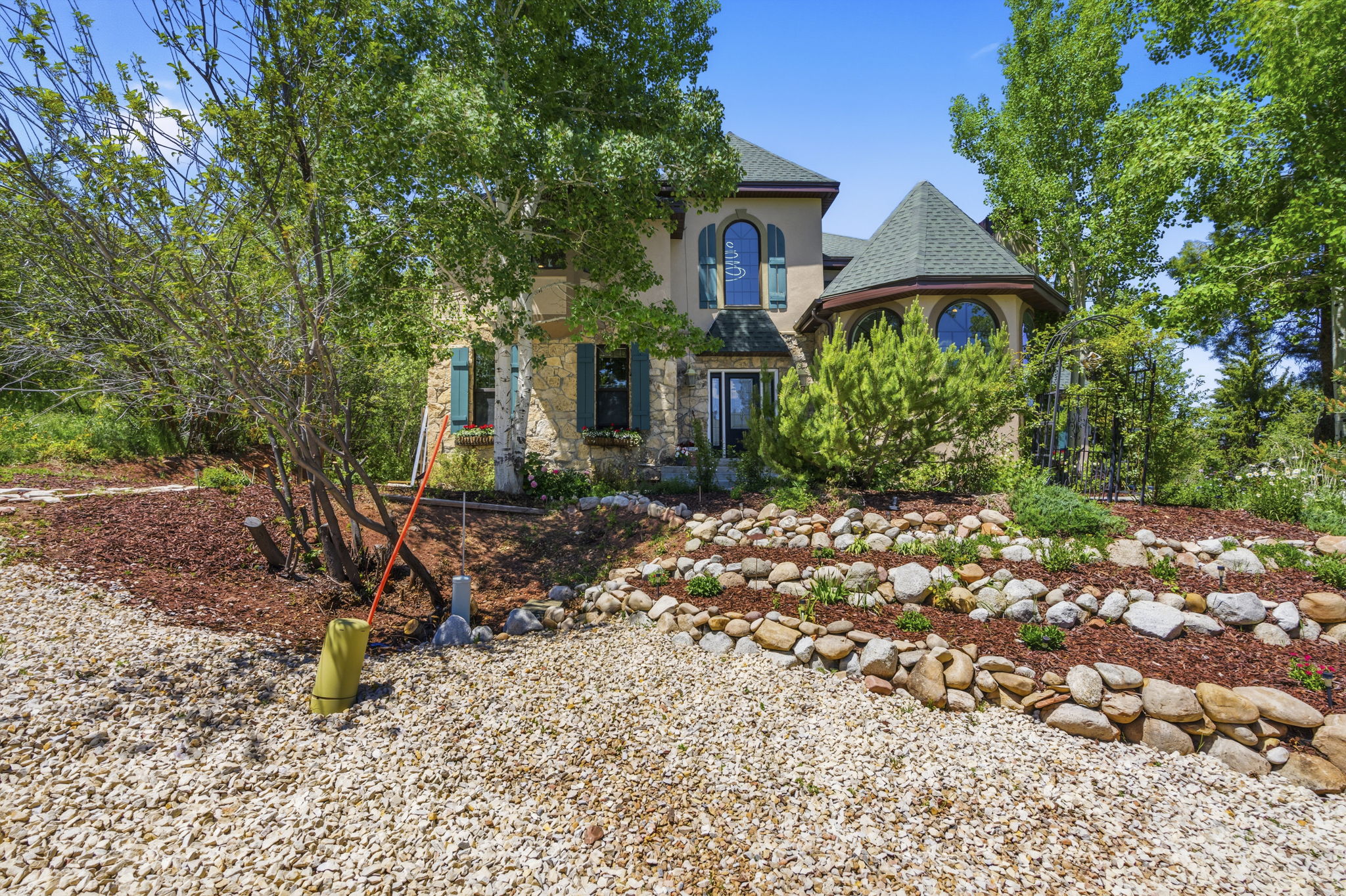 Stone and stucco exterior with a prominent turret, arched windows, and green functional shutters
