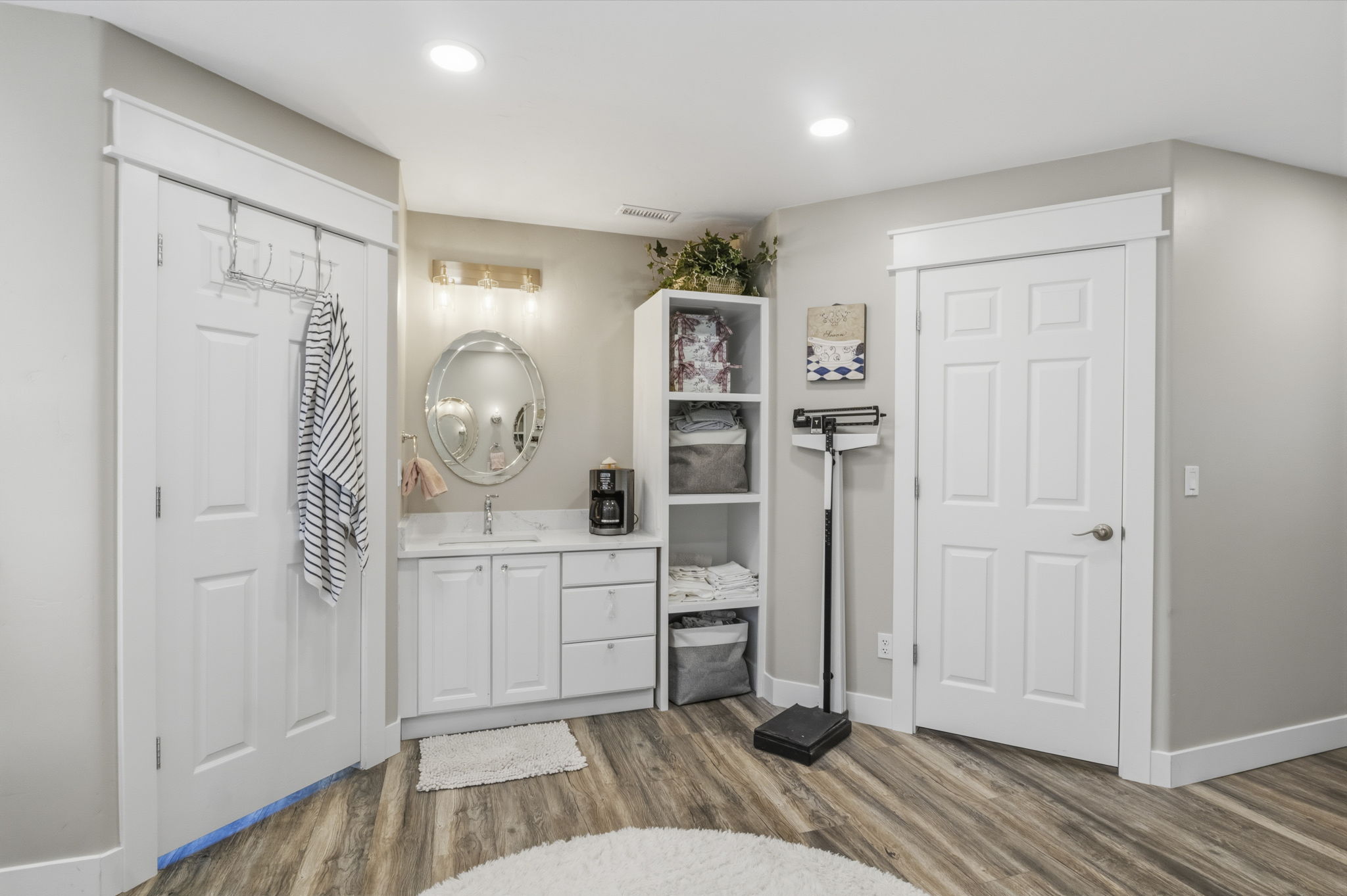 Vanity area featuring a built-in white cabinet with a white countertop, undermount sink, and wall-mounted vanity lighting