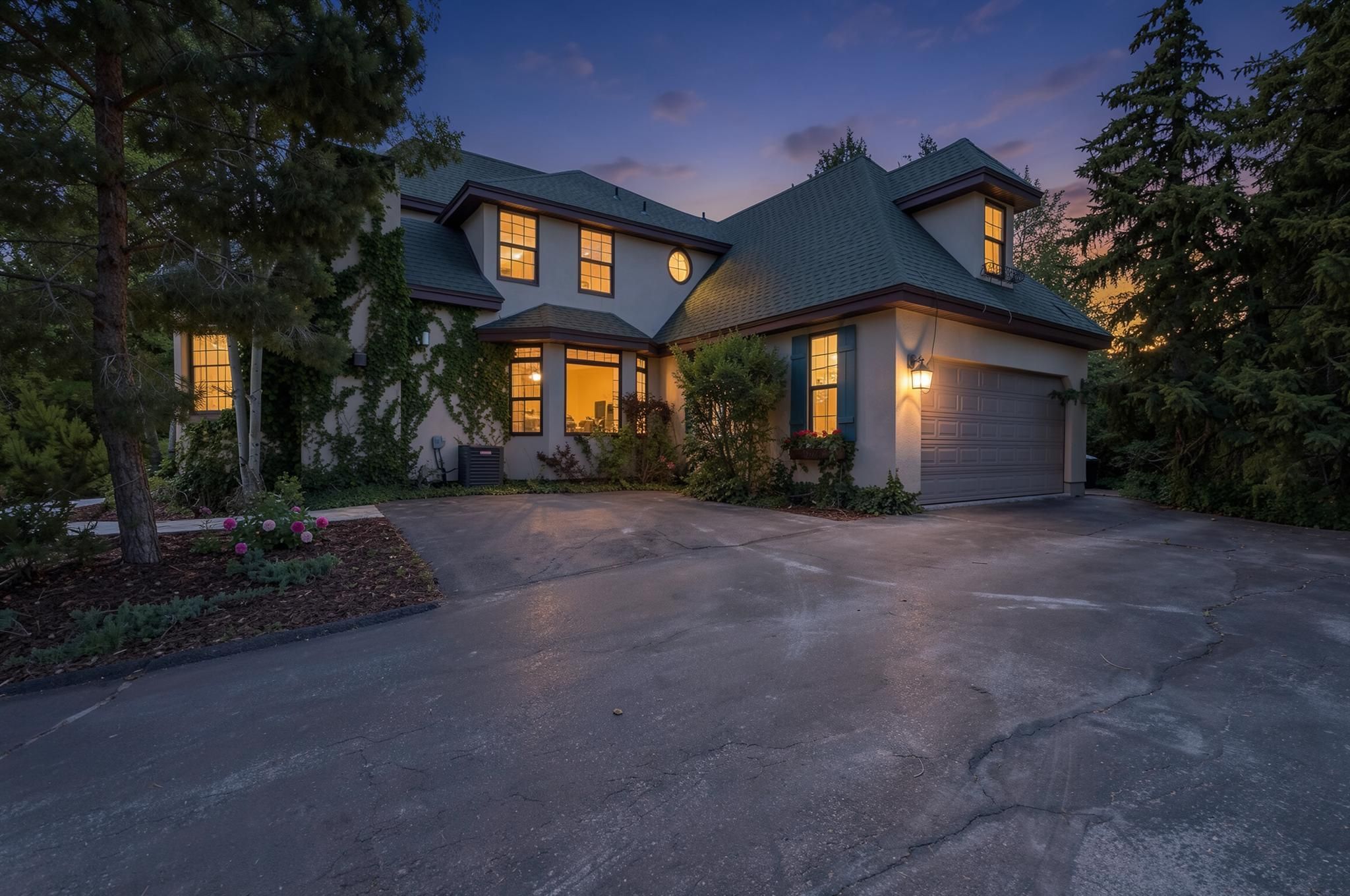 Stucco exterior featuring multiple window styles, a prominent attached garage, dormer windows, and a bay window