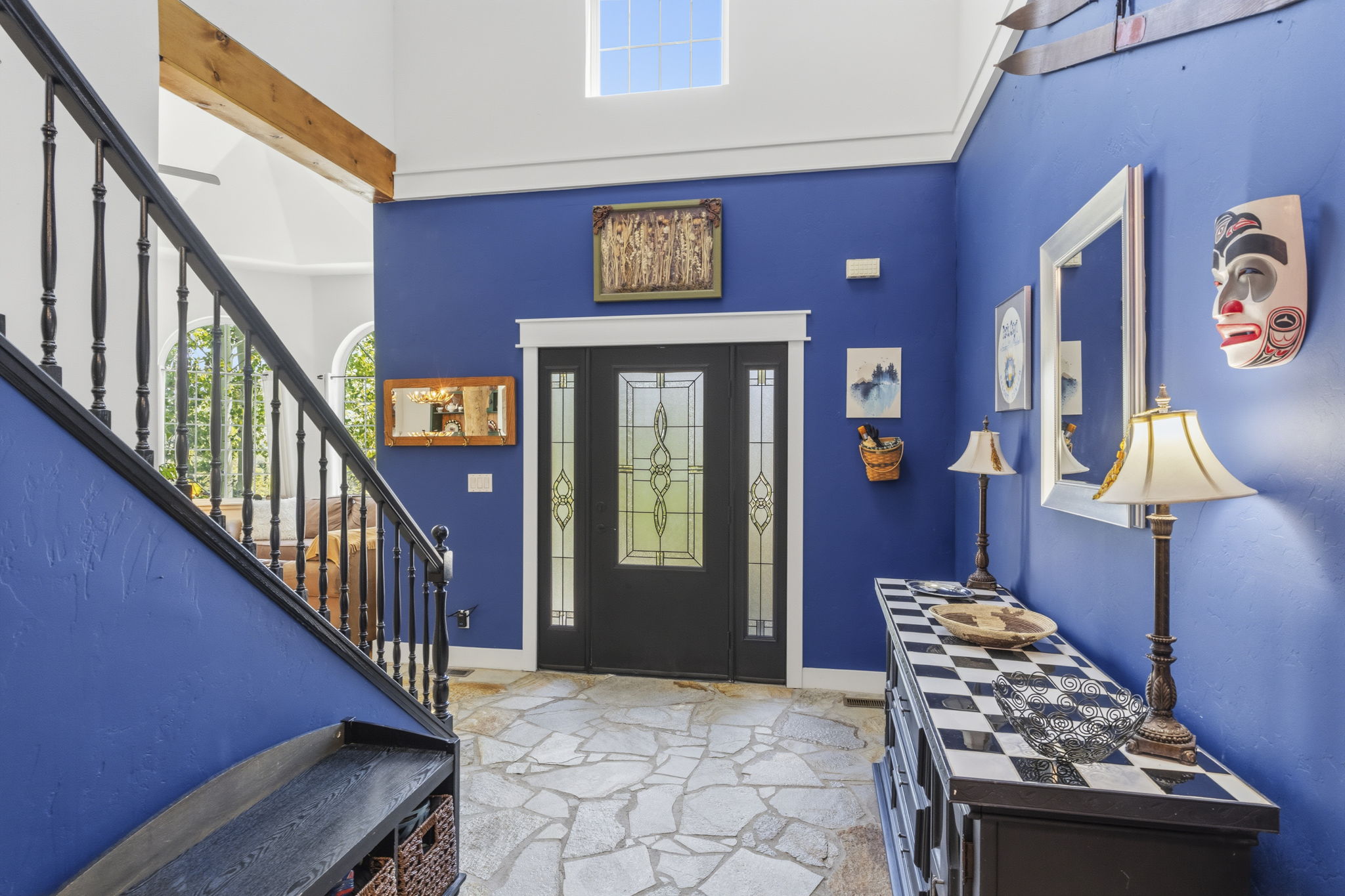 Entryway featuring natural stone flooring, a multi-pane front door with decorative glass, and high ceilings
