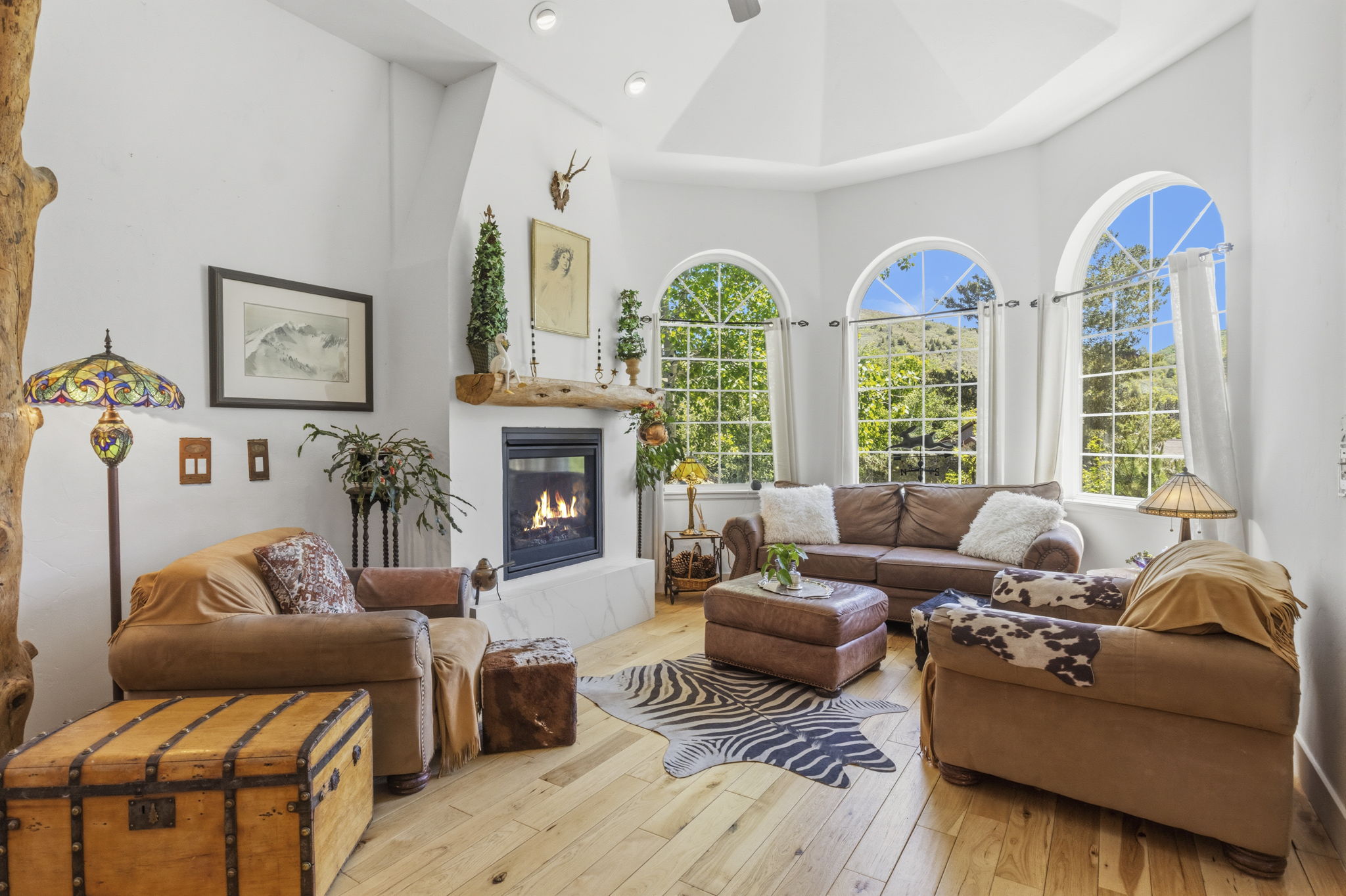 Vaulted ceiling living space featuring arched transom windows and light wood-finish flooring