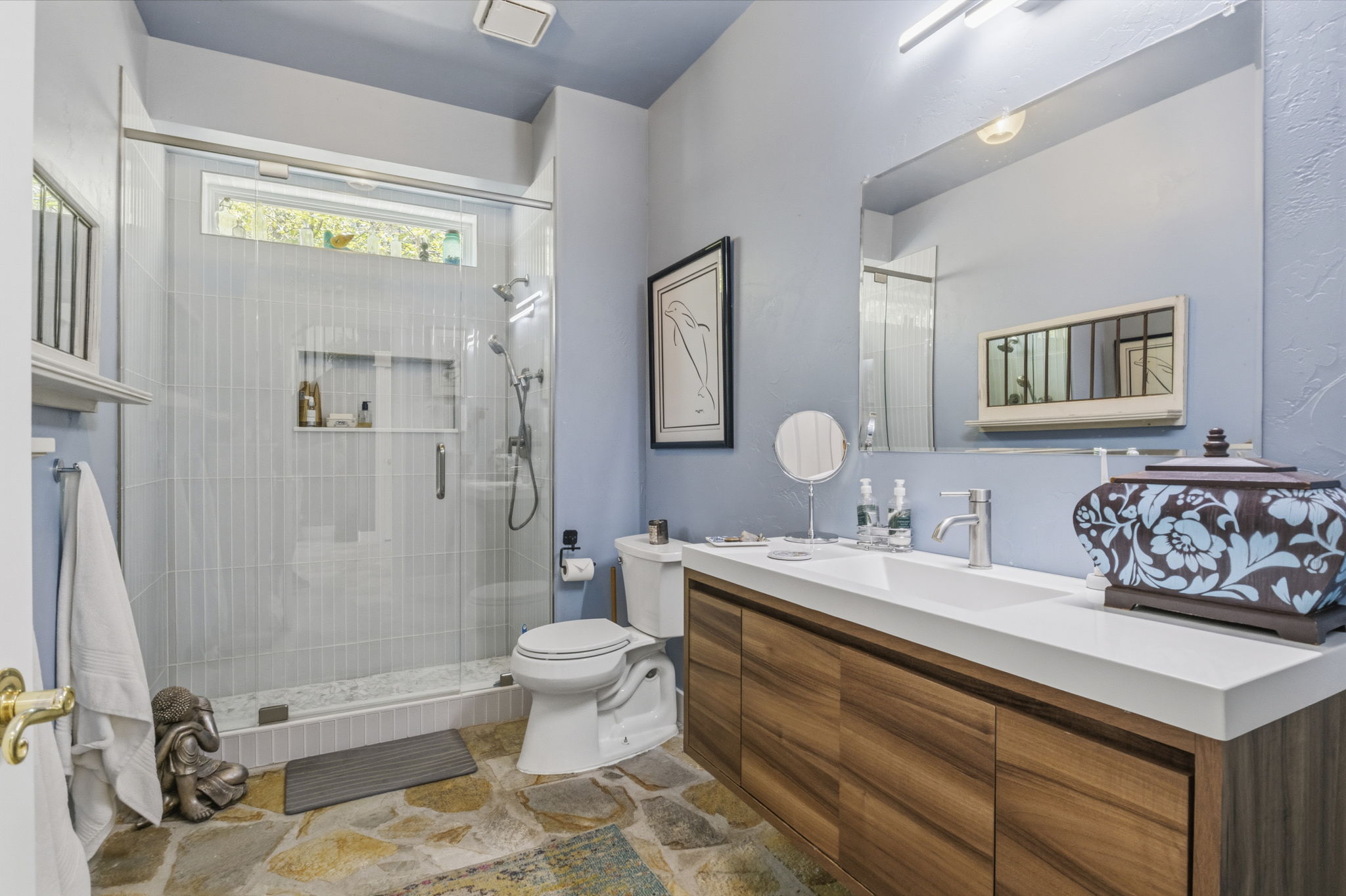 Bathroom featuring a spacious glass-enclosed shower with tiled walls and a transom window