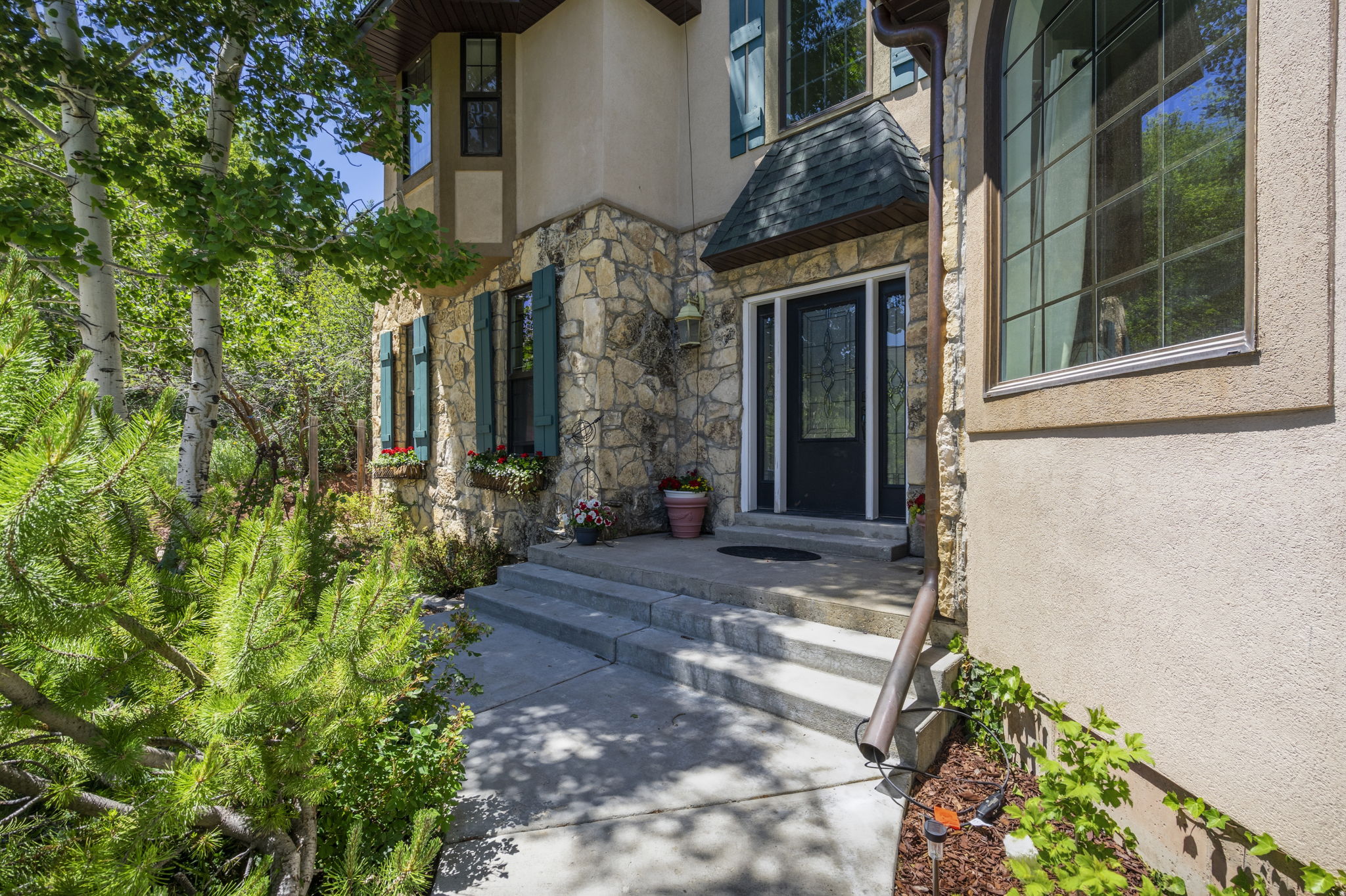Stone and stucco exterior with a dark-framed entry door and sidelights
