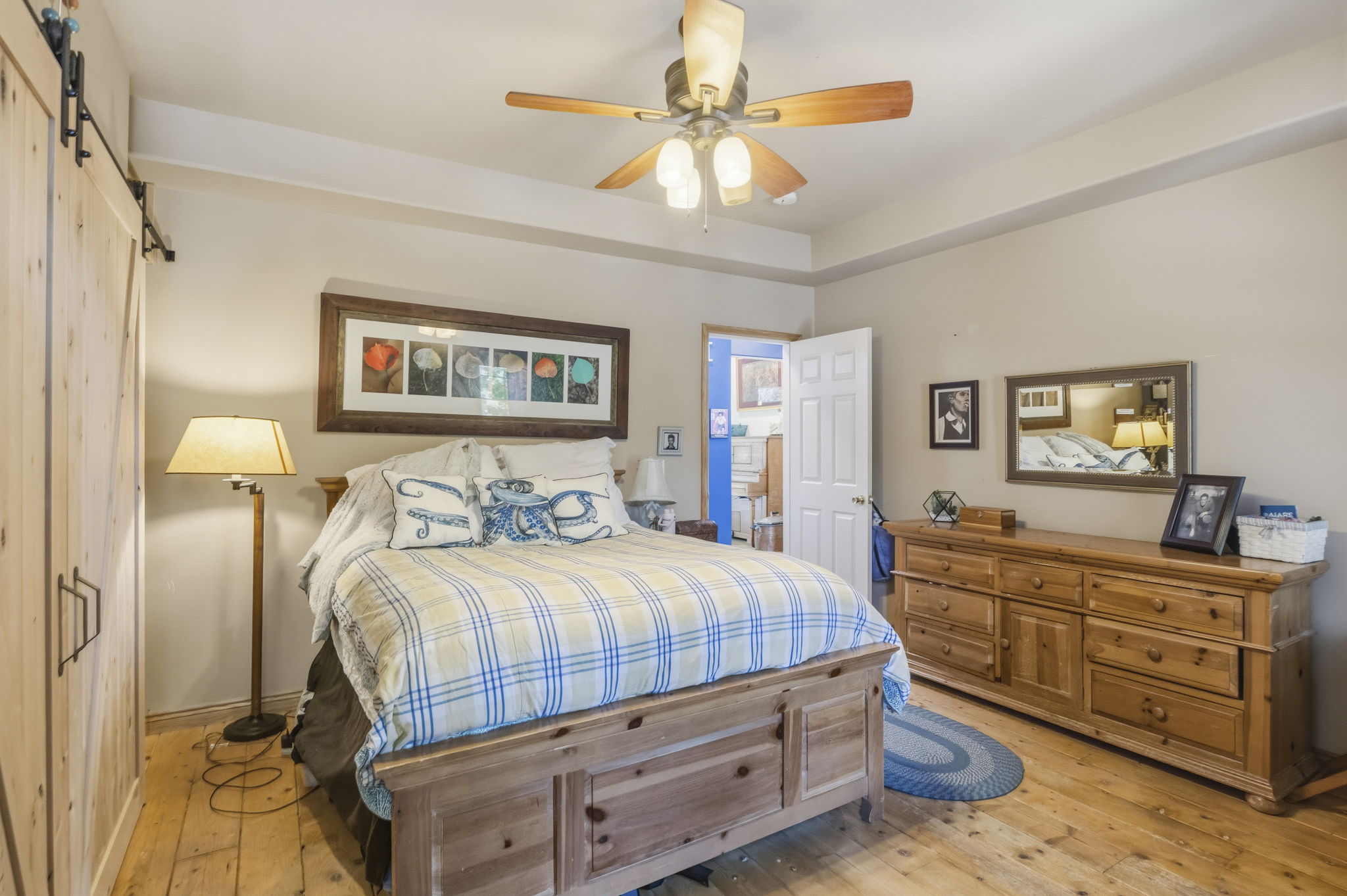 Spacious room featuring wood-finish flooring, a tray ceiling, and a ceiling fan with integrated lighting