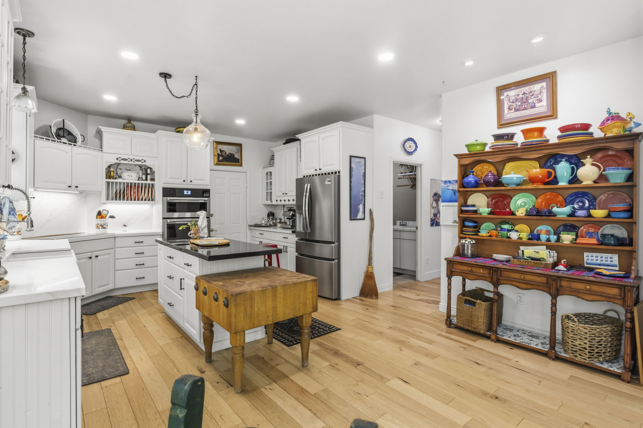 Expansive kitchen featuring wood-finish flooring, white cabinetry, and a central island with a dark countertop