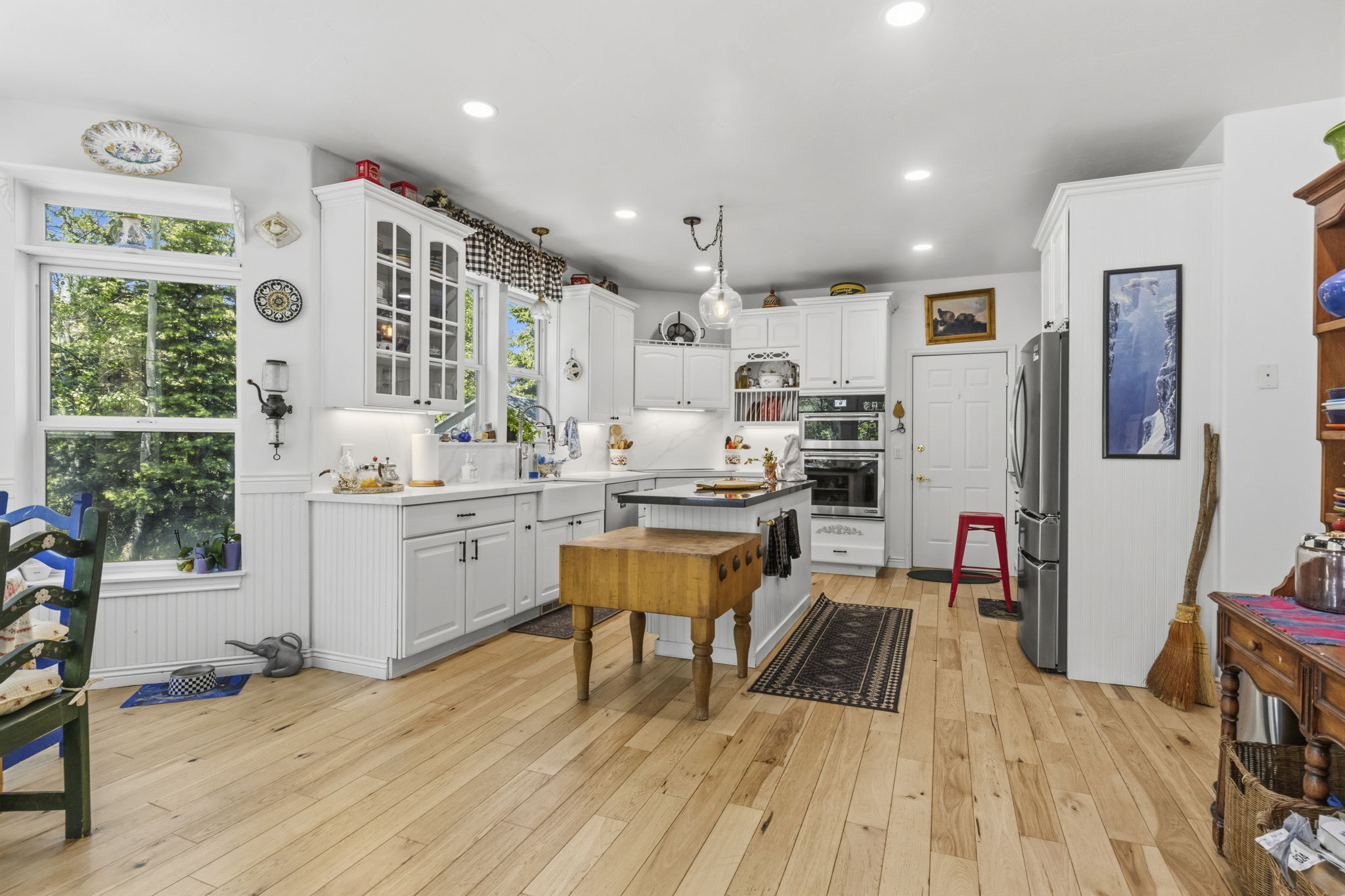 Bright kitchen featuring light wood-finish flooring, white cabinetry, a built-in double oven, and recessed lighting