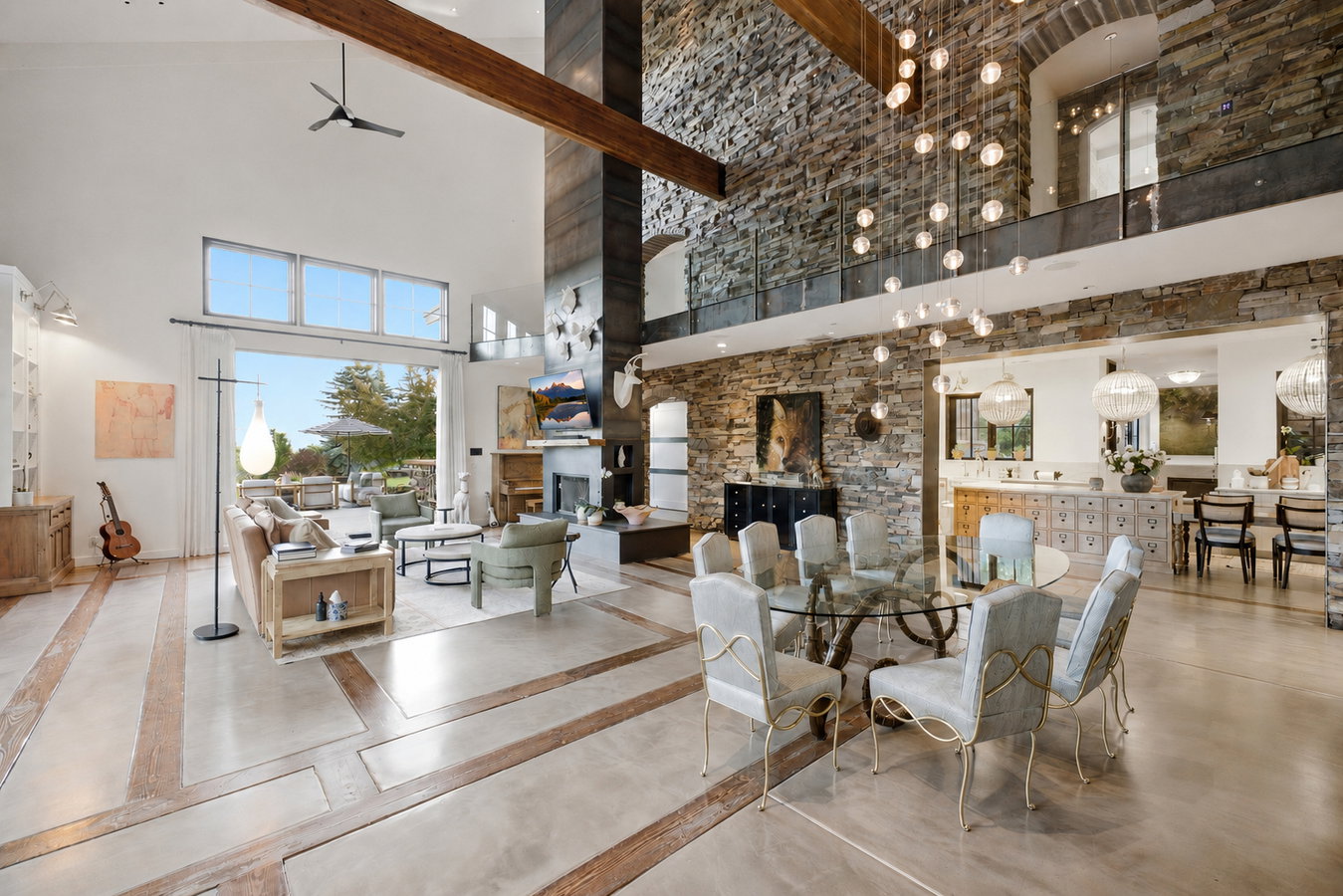 Vaulted great room featuring stone accent walls, high ceilings with exposed wood beams, and a fireplace with a stone surround