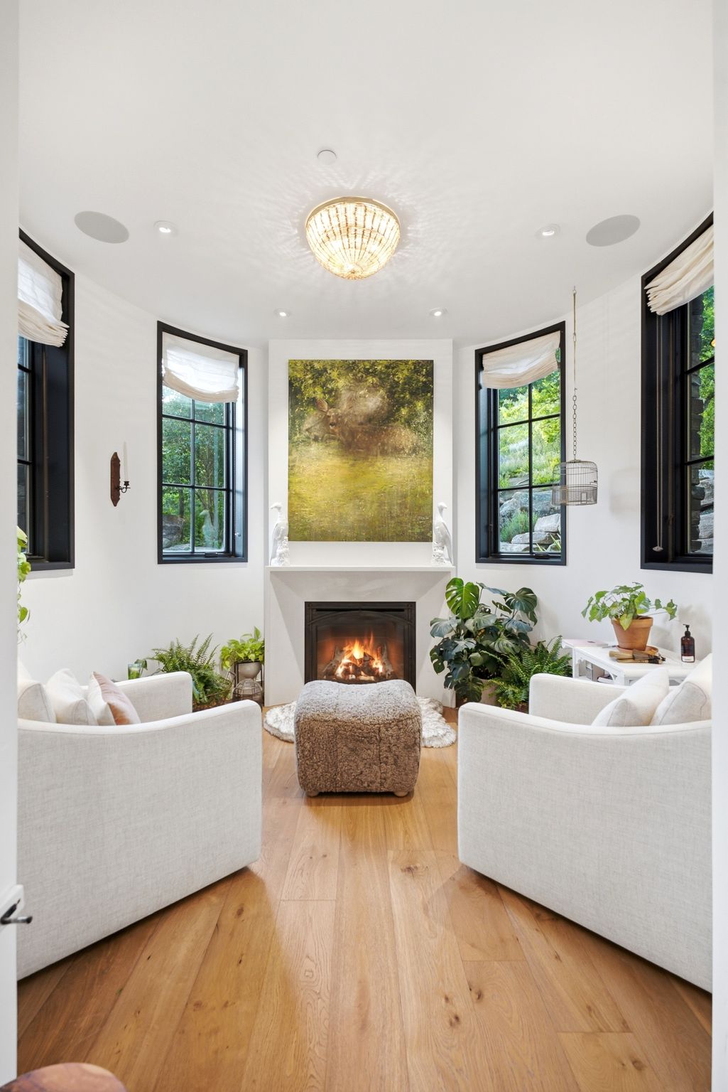 Integrated fireplace with a white mantel, framed by two large windows