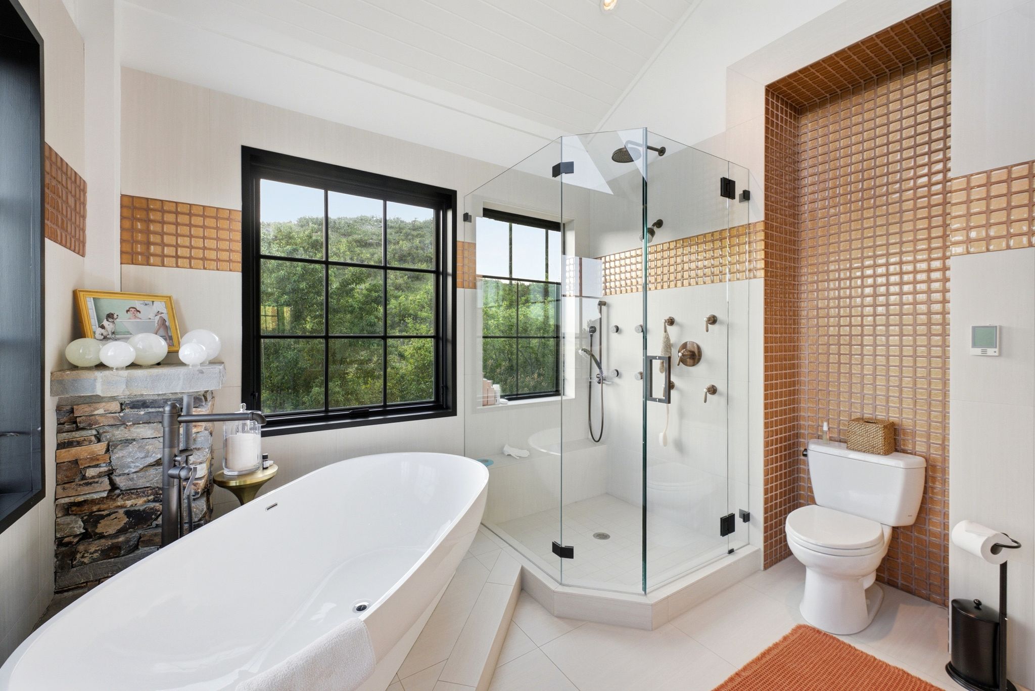Freestanding soaking tub complemented by a stone-clad feature