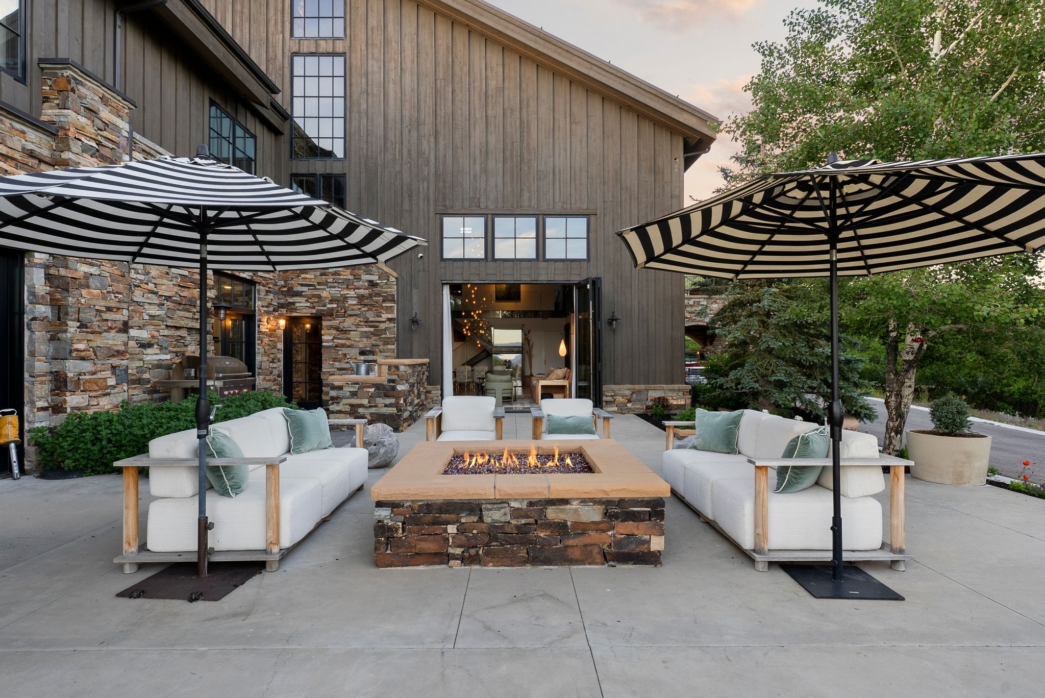 Spacious outdoor patio featuring a stone-clad fire pit, concrete surface, and direct access to the interior via large folding doors
