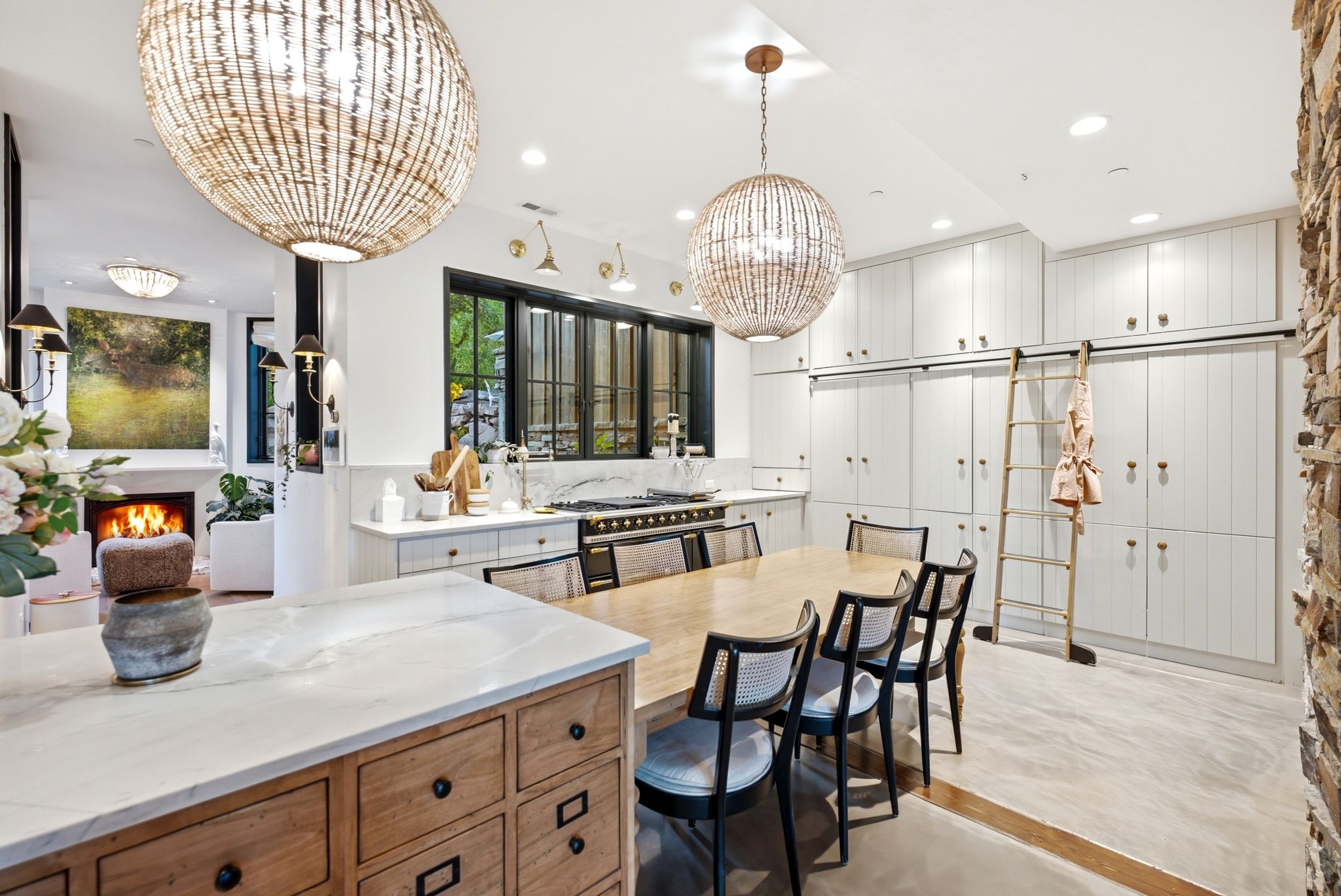 Gourmet kitchen featuring extensive white cabinetry with gold-toned hardware, an oversized central island with wood-finish drawers, and a professional-grade range