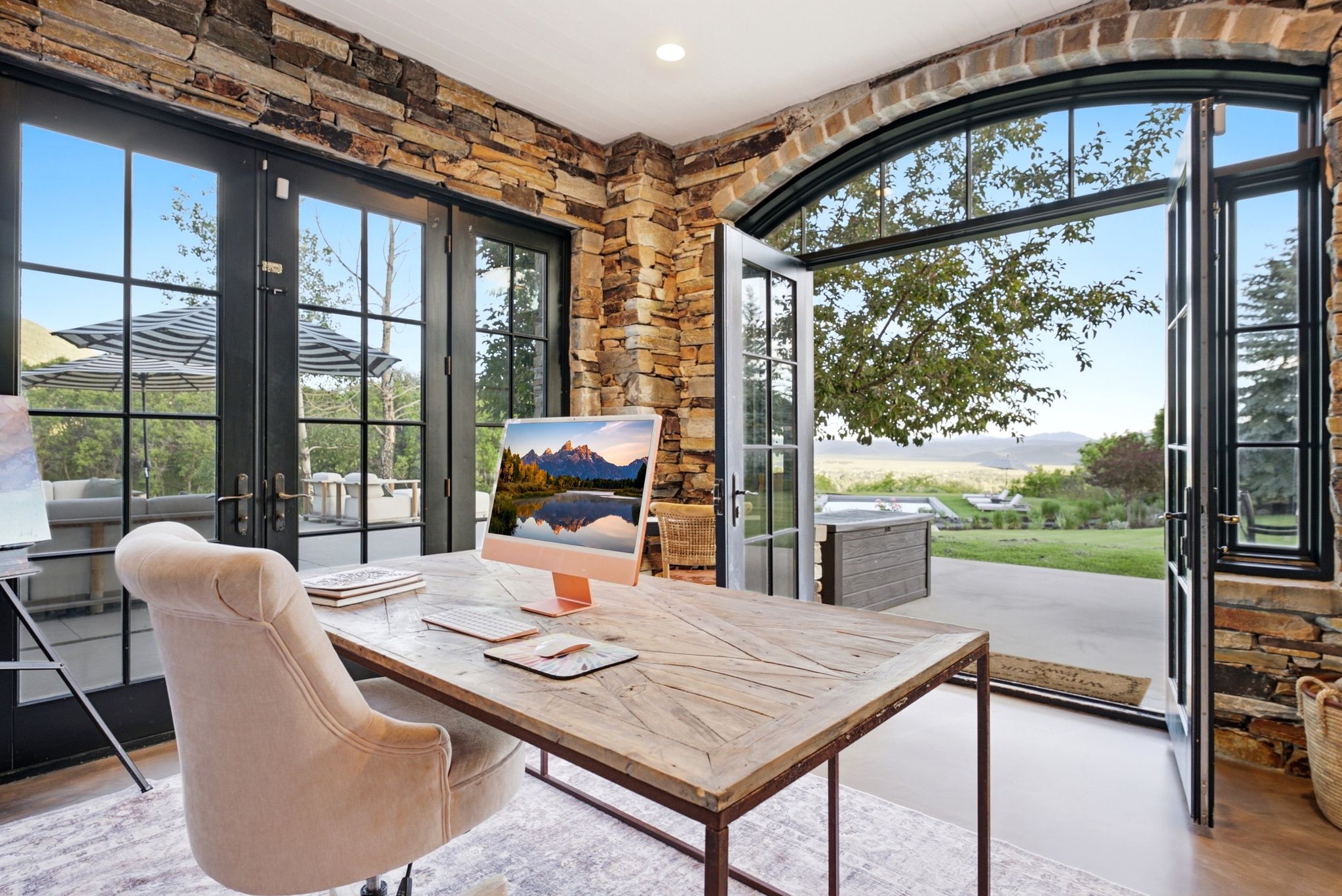Room featuring stone accent walls and two sets of black-framed French doors