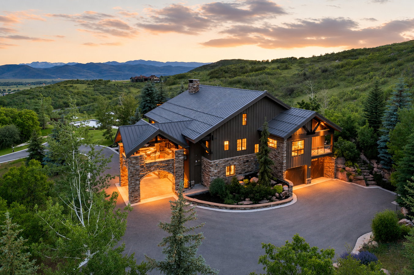 Mountain contemporary residence featuring a stone and board-and-batten exterior, dark metal roof, and an arched porte-cochère