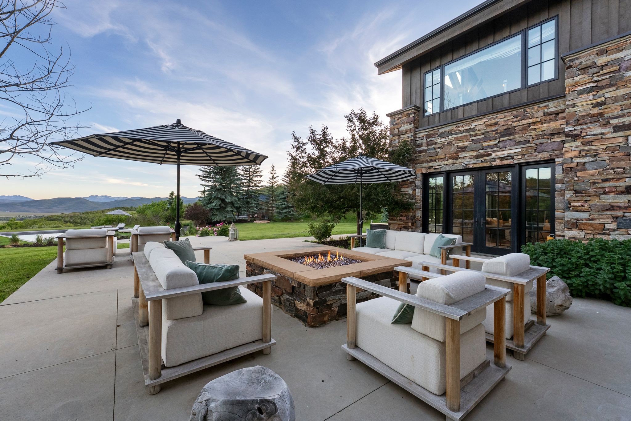 Expansive outdoor patio featuring a built-in fire pit with stone and wood-finish detailing
